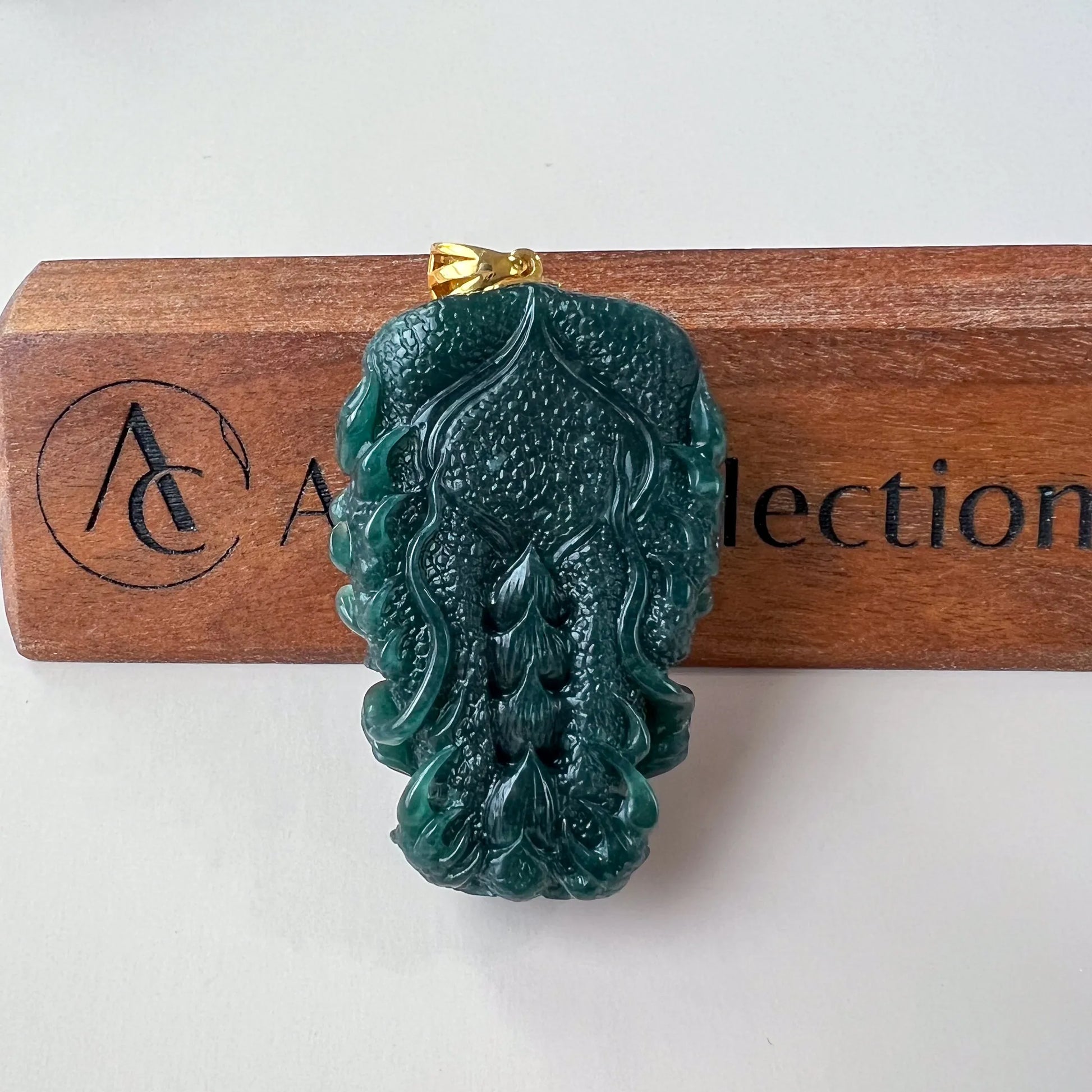 Back view of dark green Natural Jade pendant showing flowing relief carving and gold-tone bail