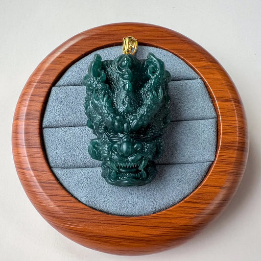 Front view of carved jade dragon pendant in round wooden gift box with gray lining