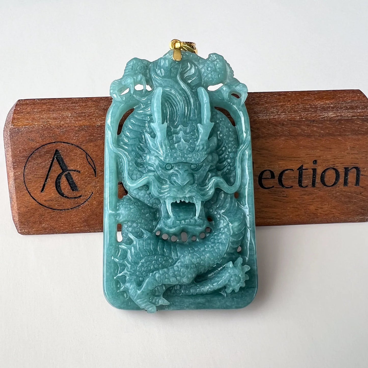 Front view of carved turquoise dragon pendant on wooden display stand