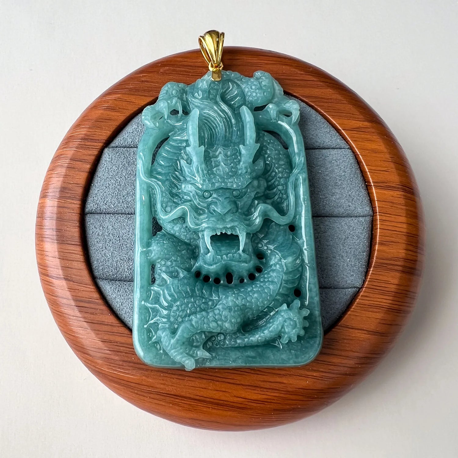 Front view of carved dragon pendant displayed in round wood presentation box
