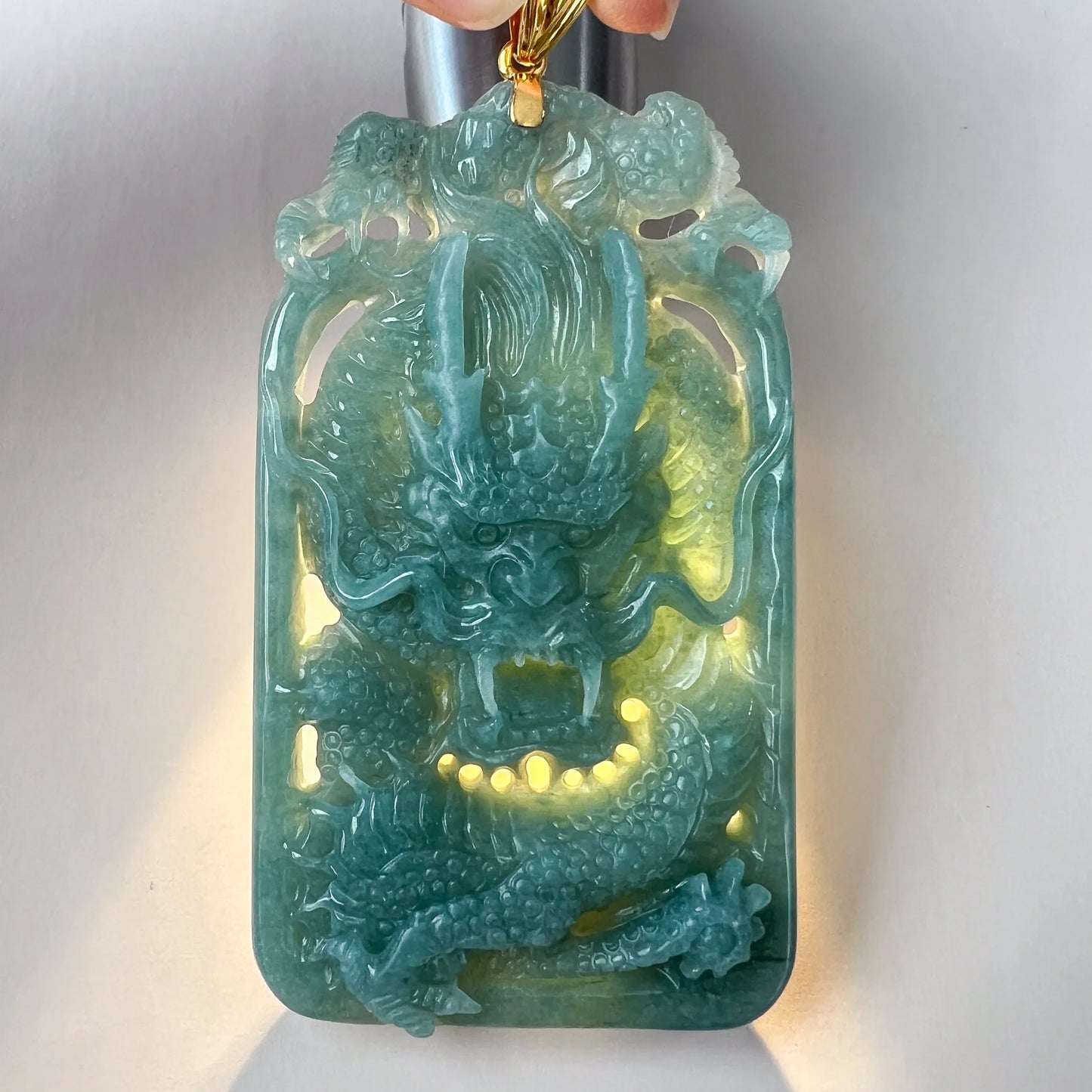 Front view of translucent carved dragon pendant backlit to show stone detail