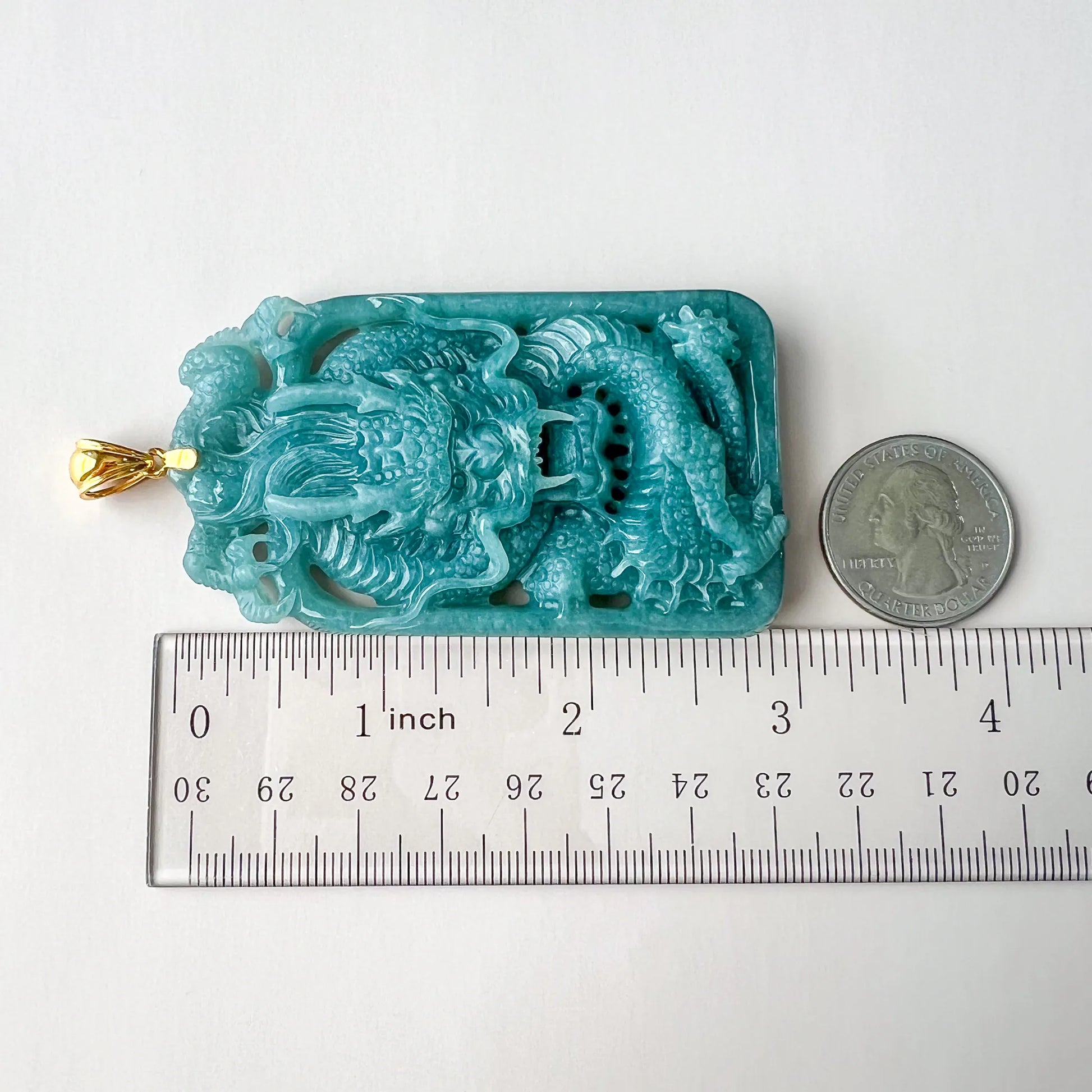 Top-down size comparison of carved dragon pendant with ruler and quarter
