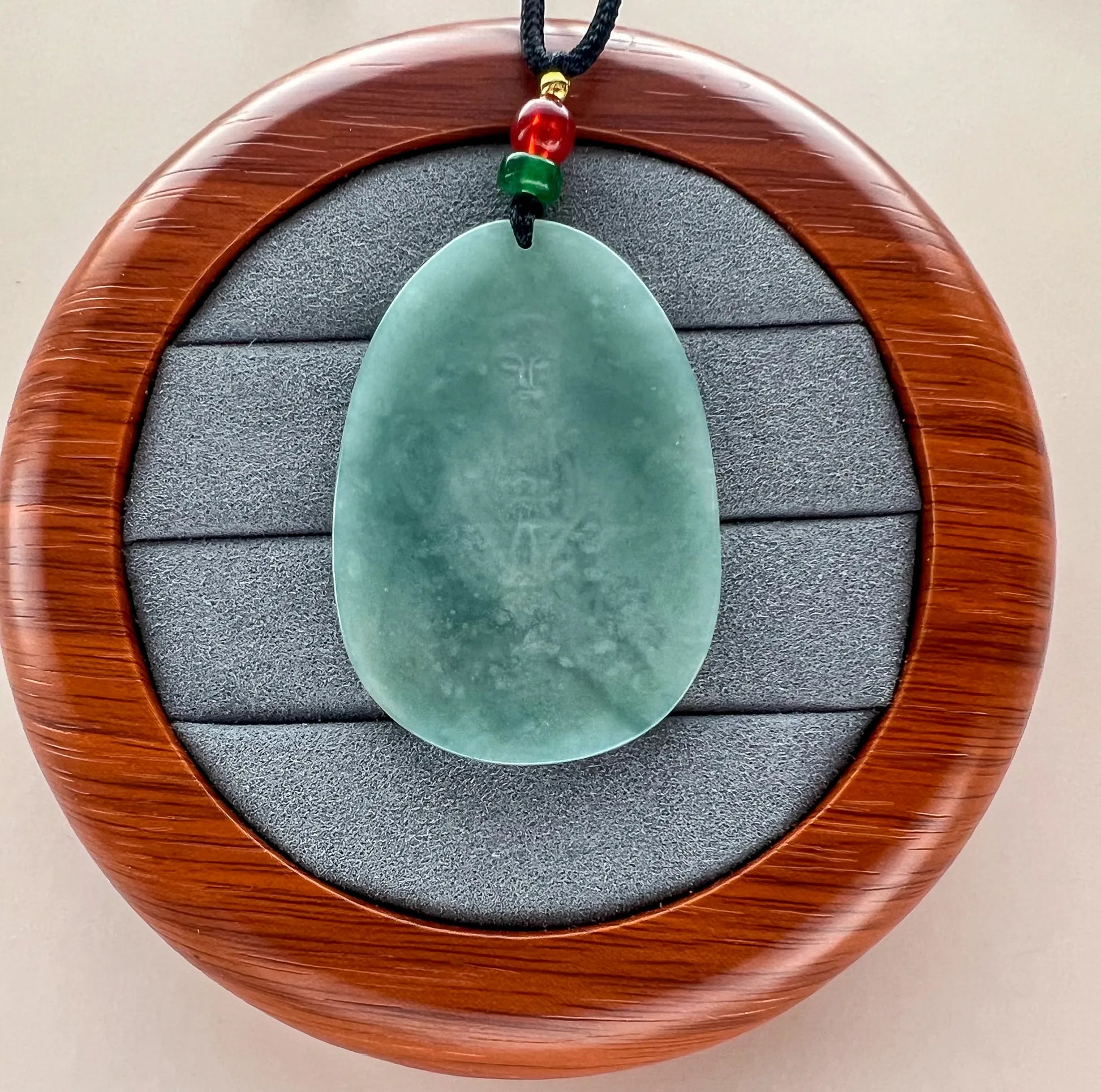 Reverse of light green Natural Jade pendant showing a smooth polished back and drilled cord opening