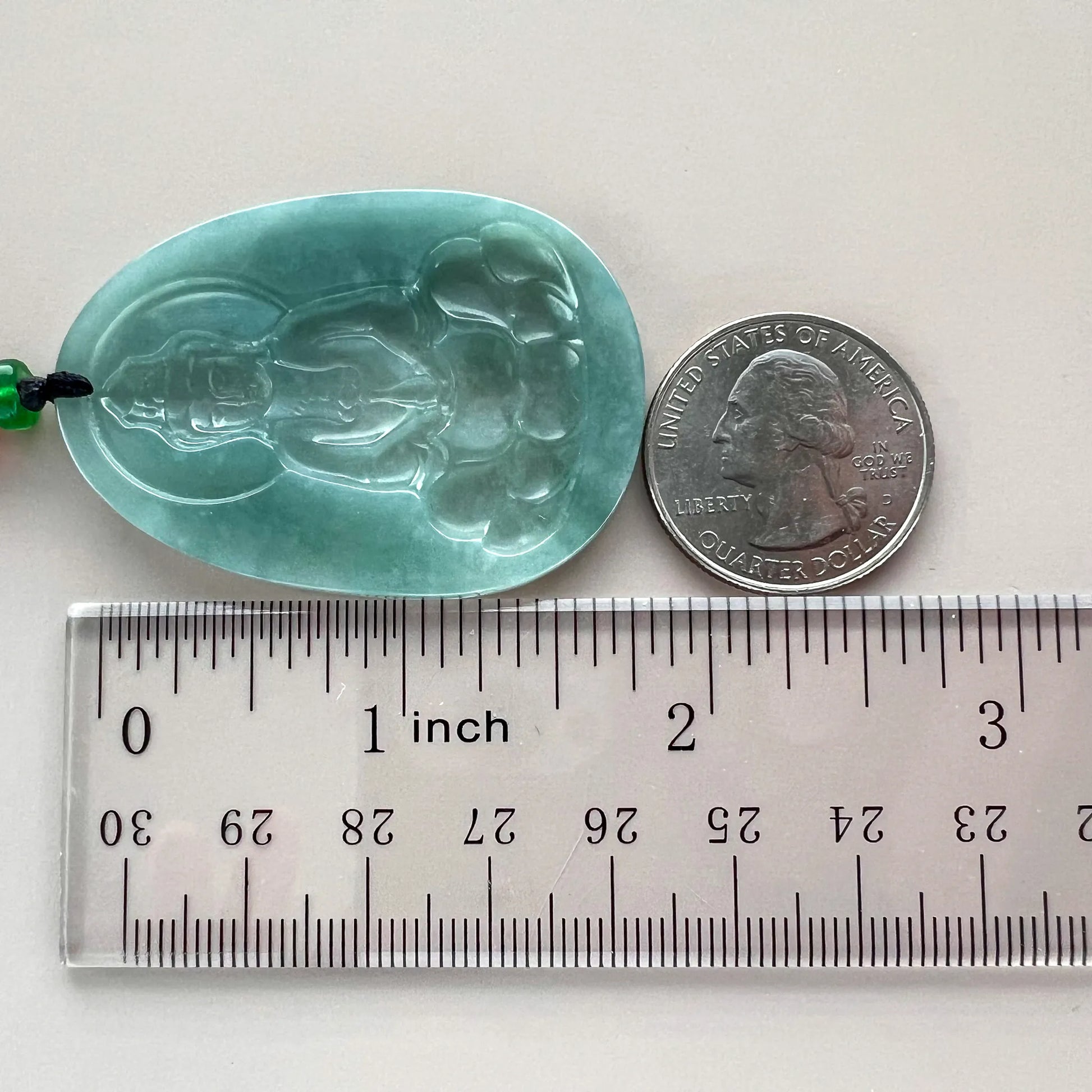 Side view jade pendant with ruler and quarter for size reference