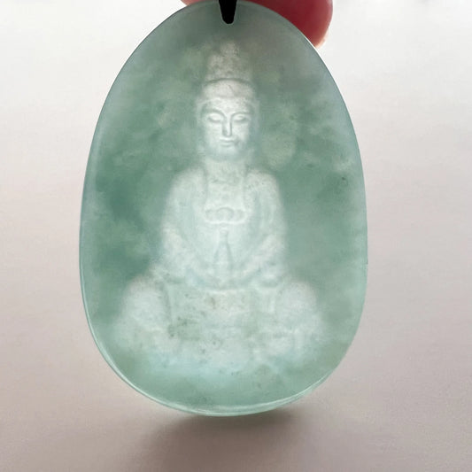 Close-up back view of translucent green jade Buddha carving pendant