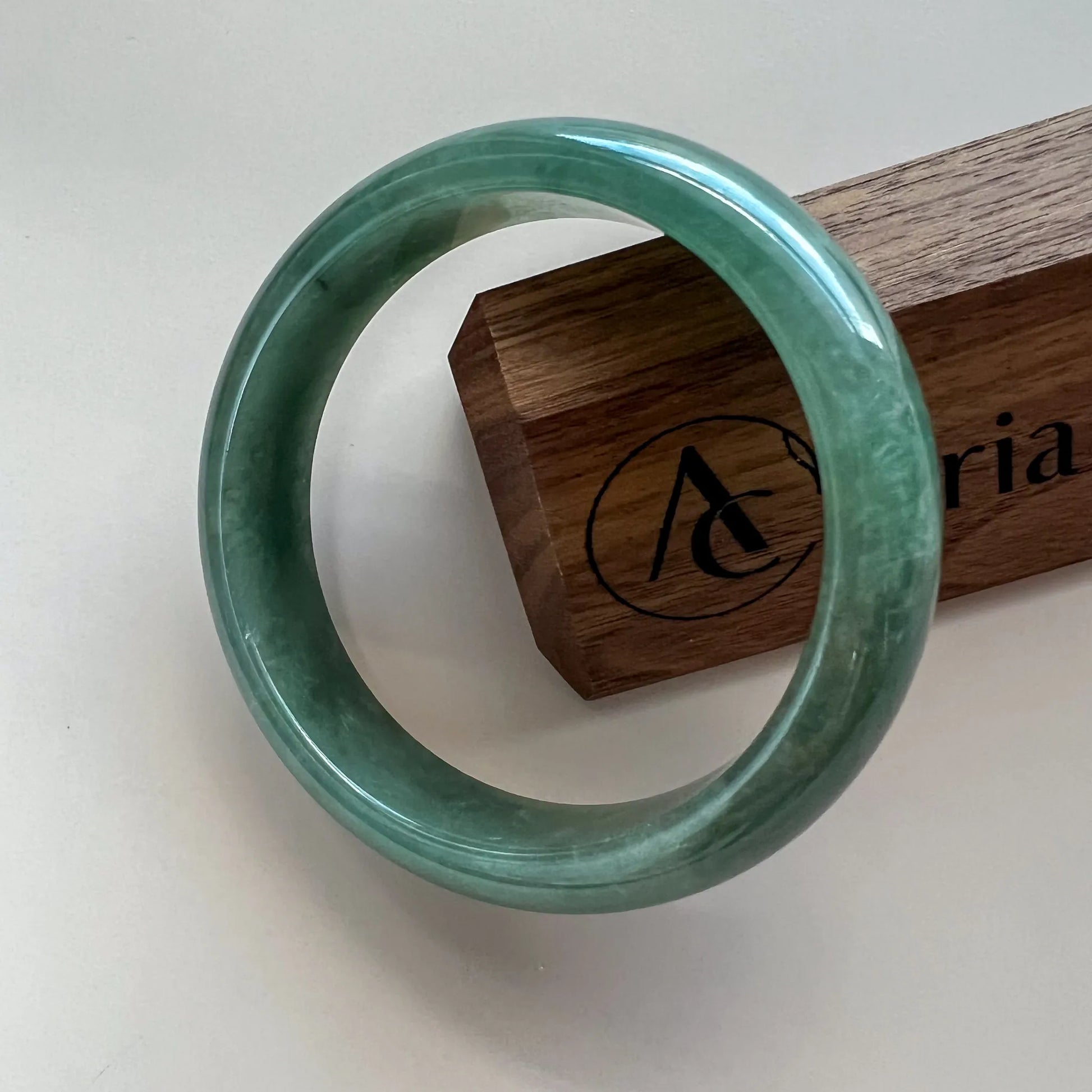 Front view of polished green jade bangle with glossy finish on display stand
