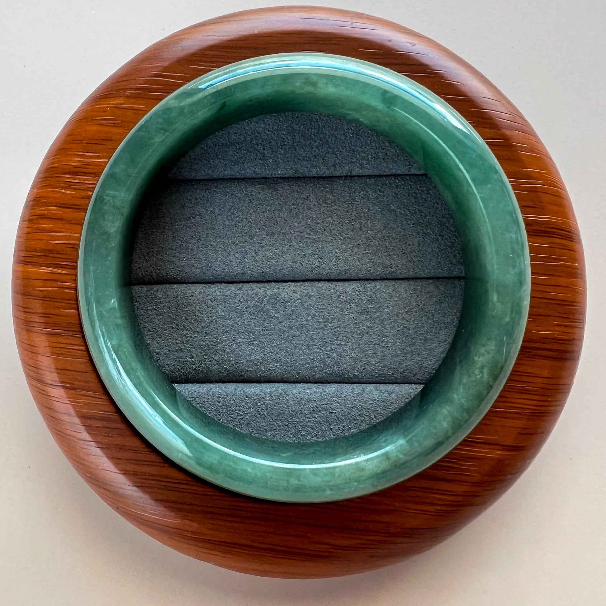 Top view of green jade bangle in wooden stand with cushioned interior