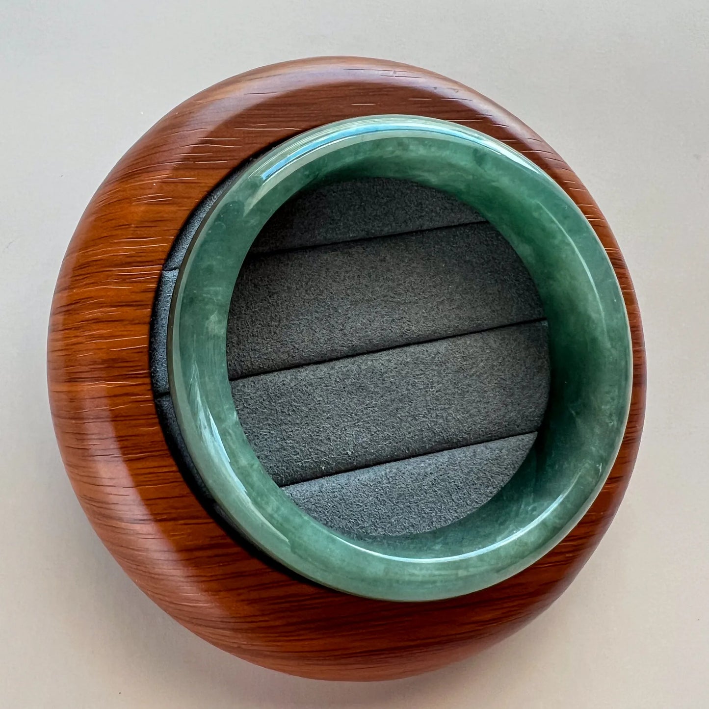 Centered top view of green jade bangle seated in rounded wooden presentation stand