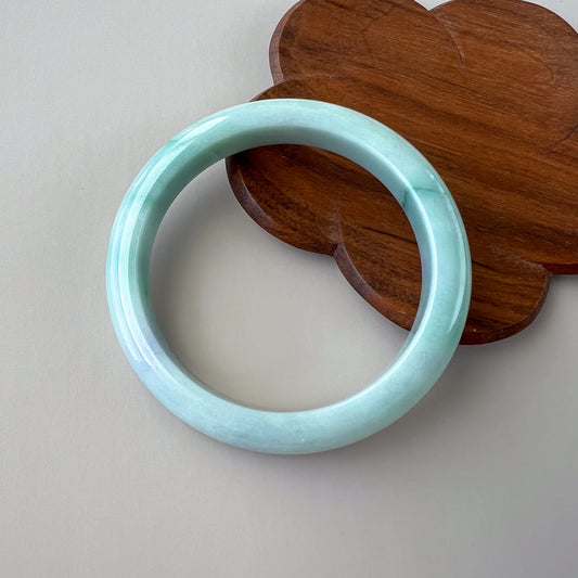 Light blue bracelet on a wooden heart-shaped object against a light gray background