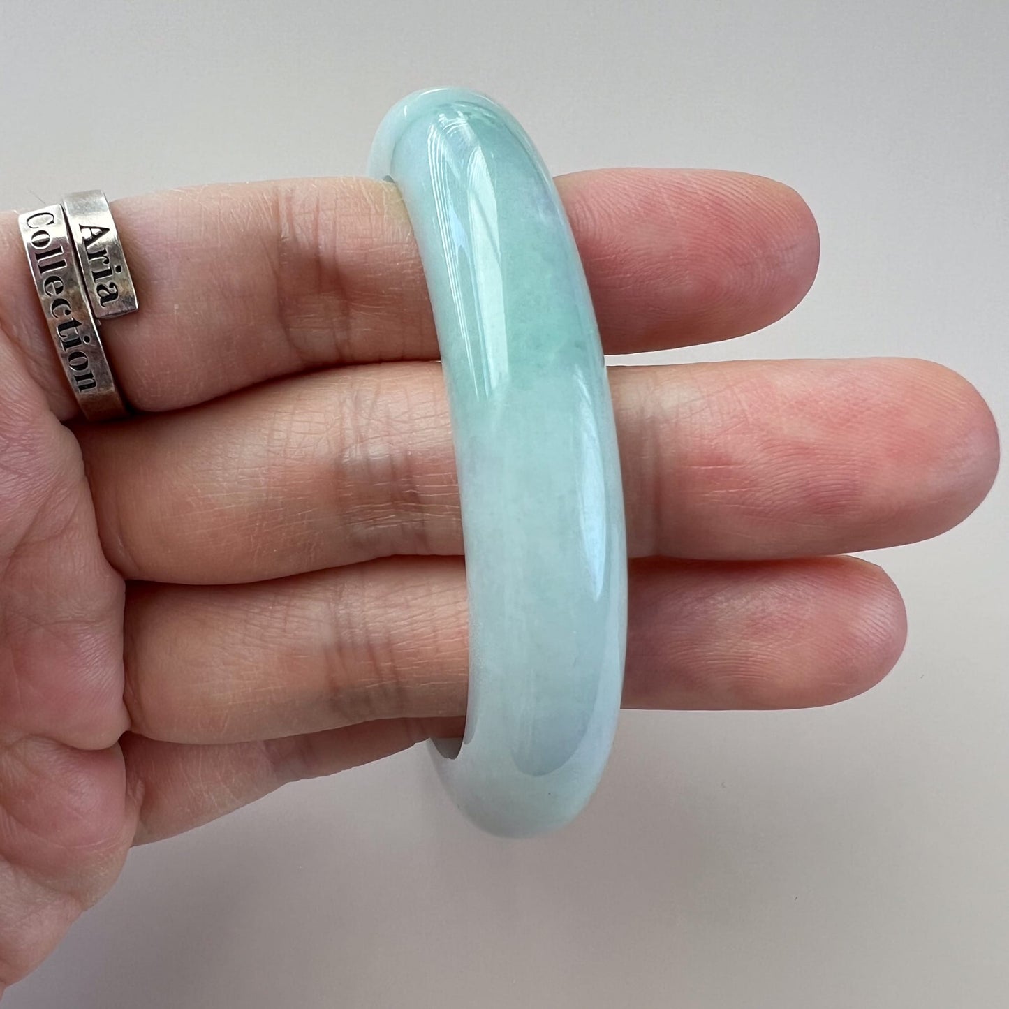 Close-up angled view of a light green Burmese Type A jadeite jade inner-flat bangle with glossy polished finish