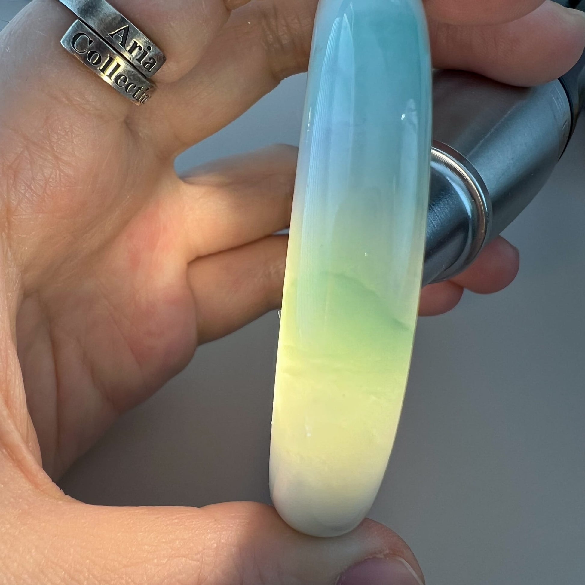 Close-up of light green Burmese type A jadeite bangle, inner-flat profile, polished translucent finish in hand