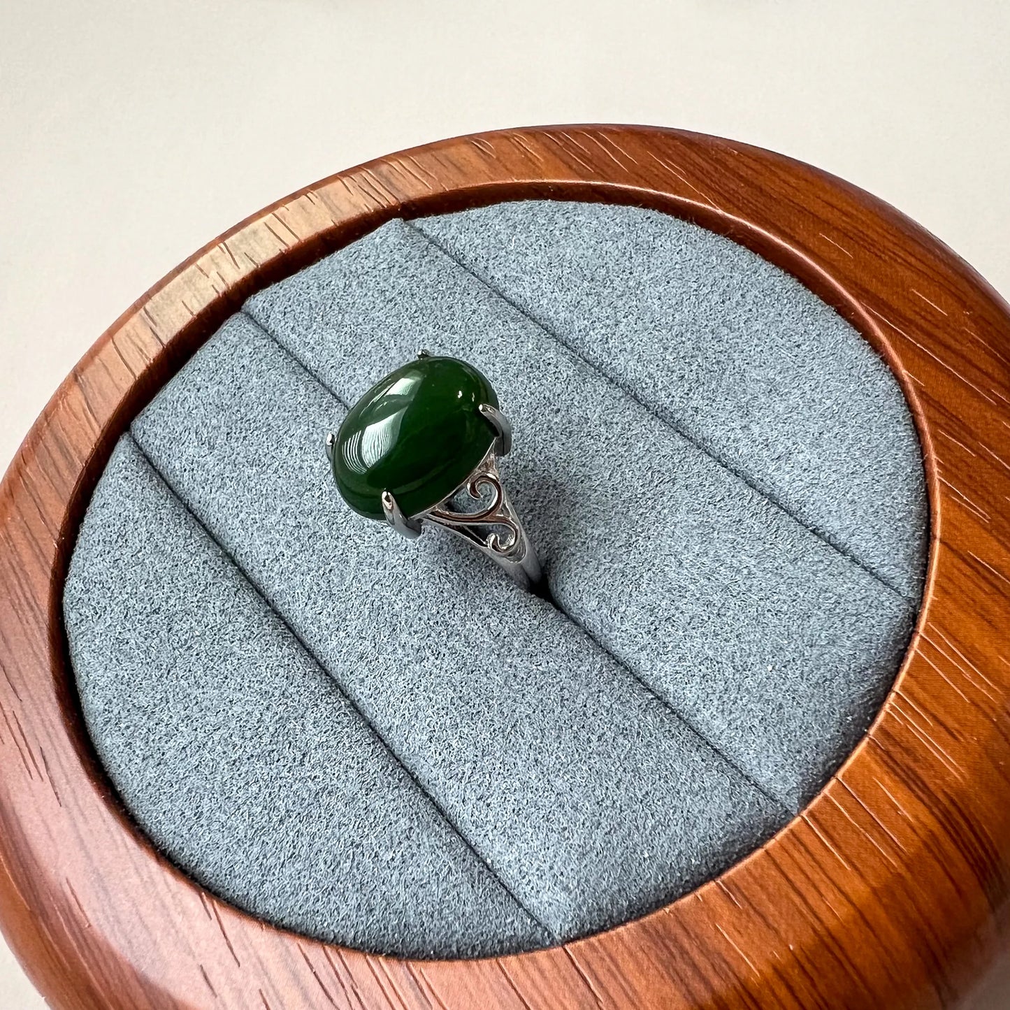 Side view of green oval cabochon ring with four-prong setting and silver-tone scroll band