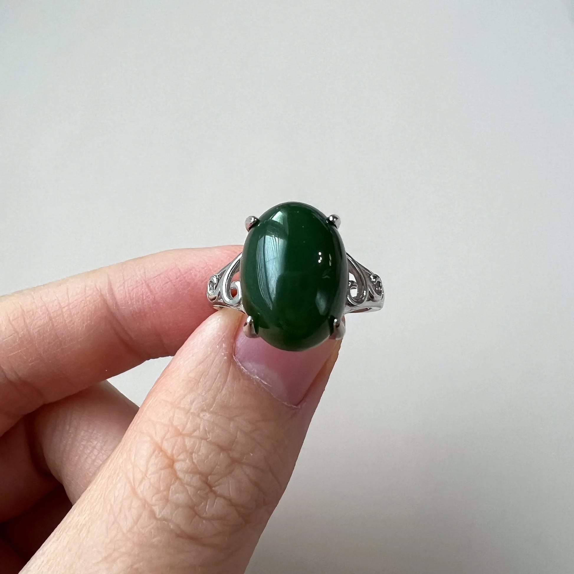 Handheld front view of green cabochon ring in polished silver setting