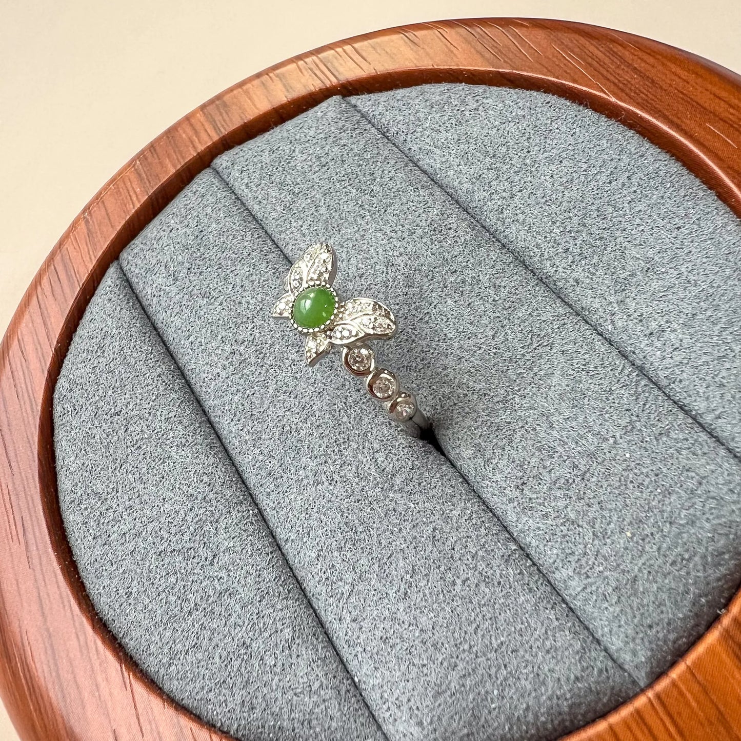 Side view of green cabochon ring showing butterfly setting and pavé-accented silver-tone band