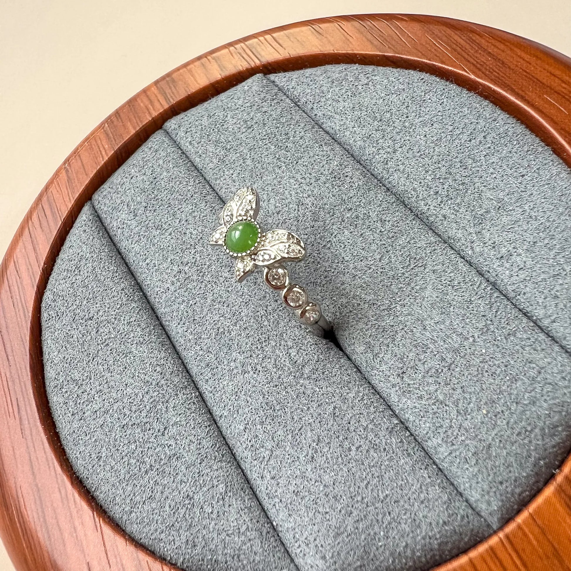 Side view of green cabochon ring showing butterfly setting and pavé-accented silver-tone band