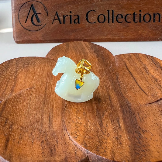 Side angle of jade horse pendant on wooden display, glossy carved stone with gold setting