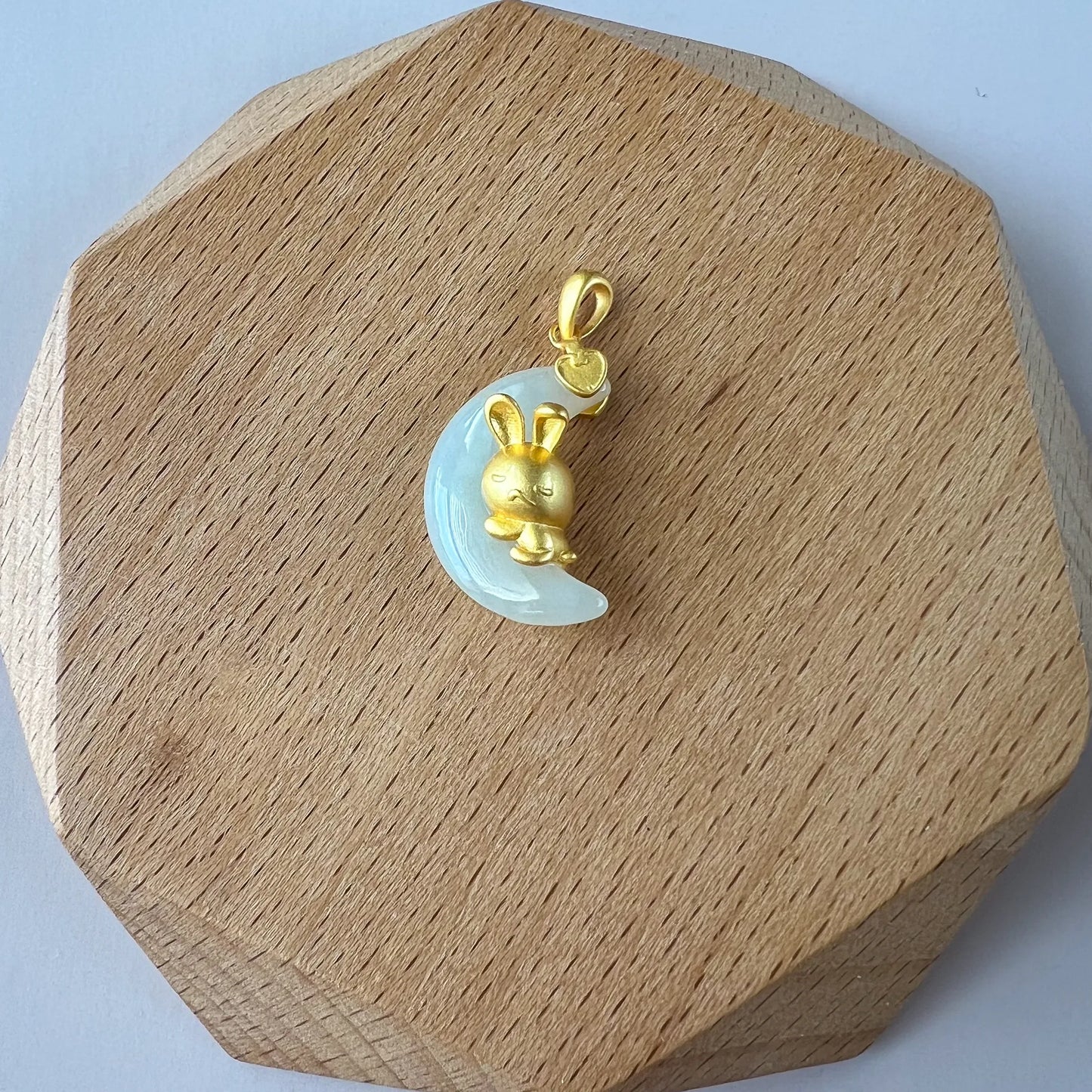 Nephrite jade moon rabbit pendant with sterling silver bail, glossy carved finish on a wooden display stand