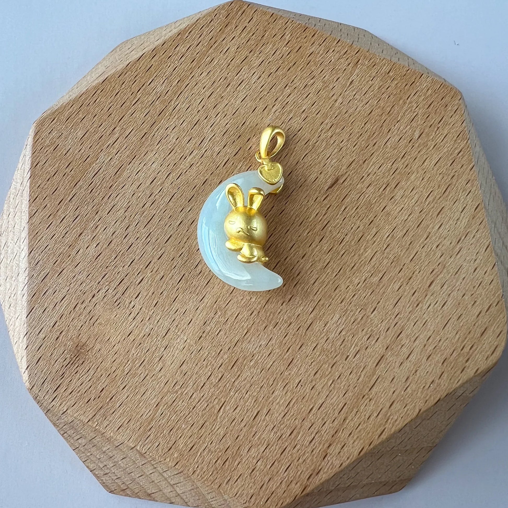 Nephrite jade moon rabbit pendant with sterling silver bail, glossy carved finish on a wooden display stand