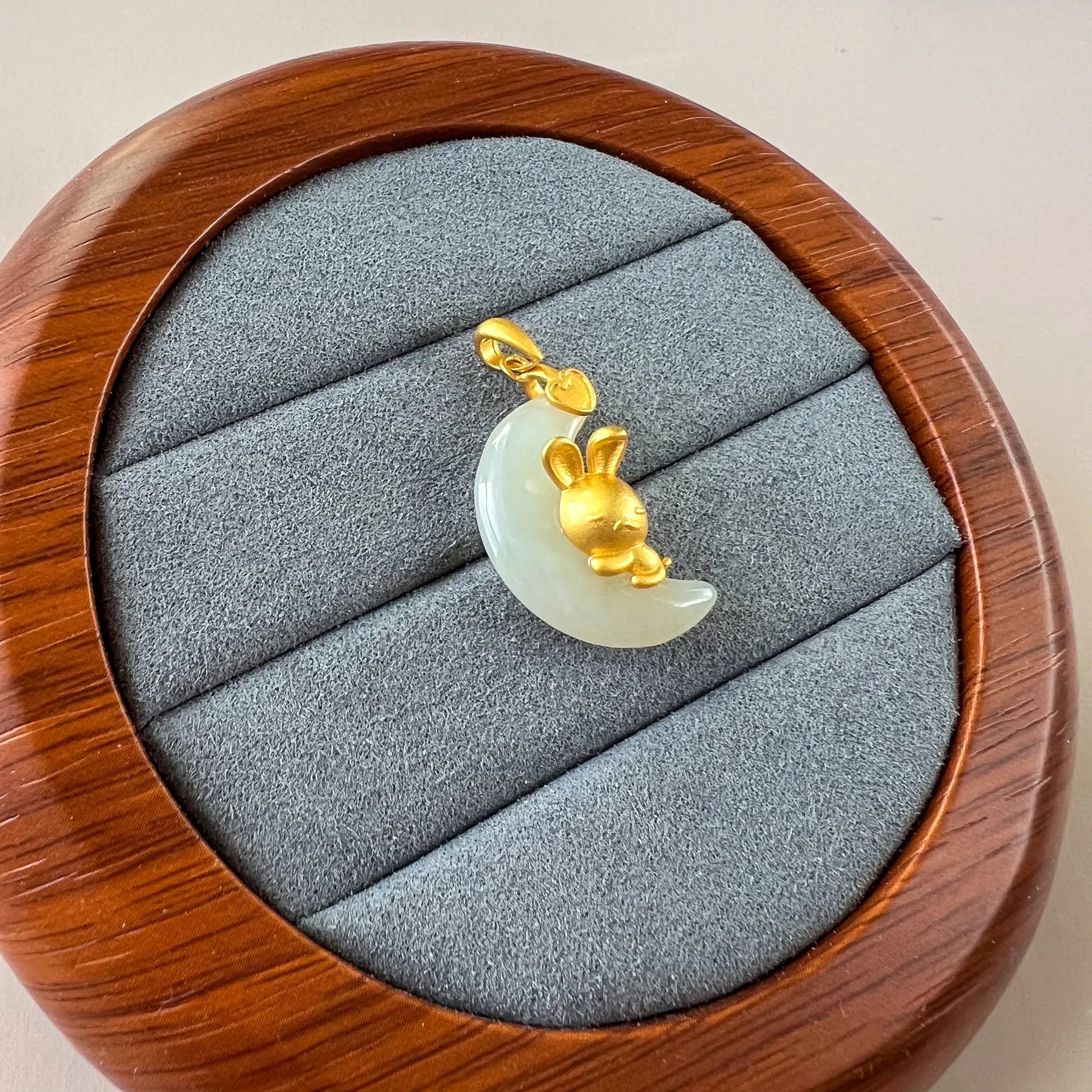 Jade rabbit nephrite pendant with sterling silver bail, shown on gray velvet jewelry tray, close-up angle