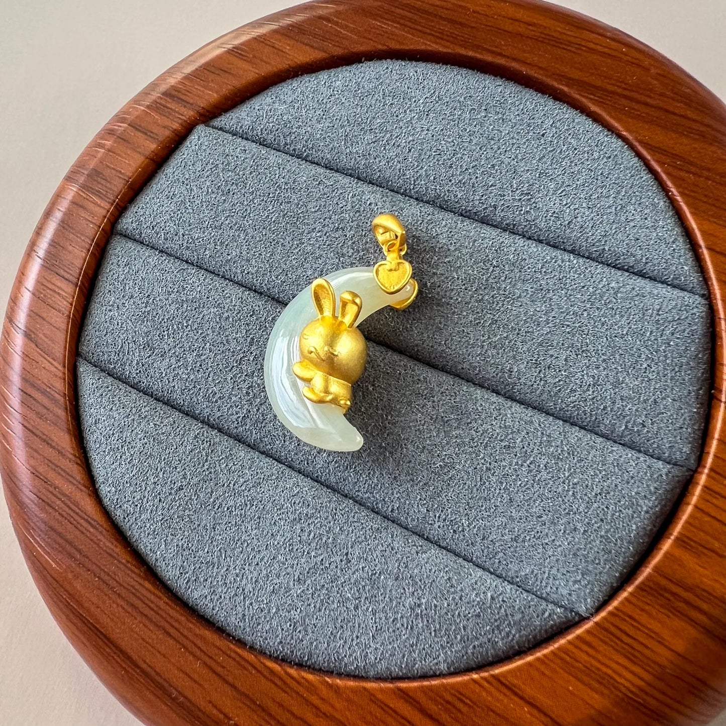Jade rabbit nephrite pendant with sterling silver, angled on gray velvet in a round wooden jewelry box