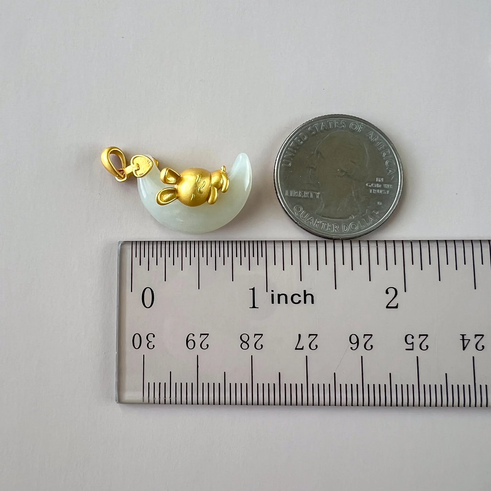 Nephrite jade rabbit pendant with gold-tone sterling silver bail, shown beside a quarter and ruler for scale