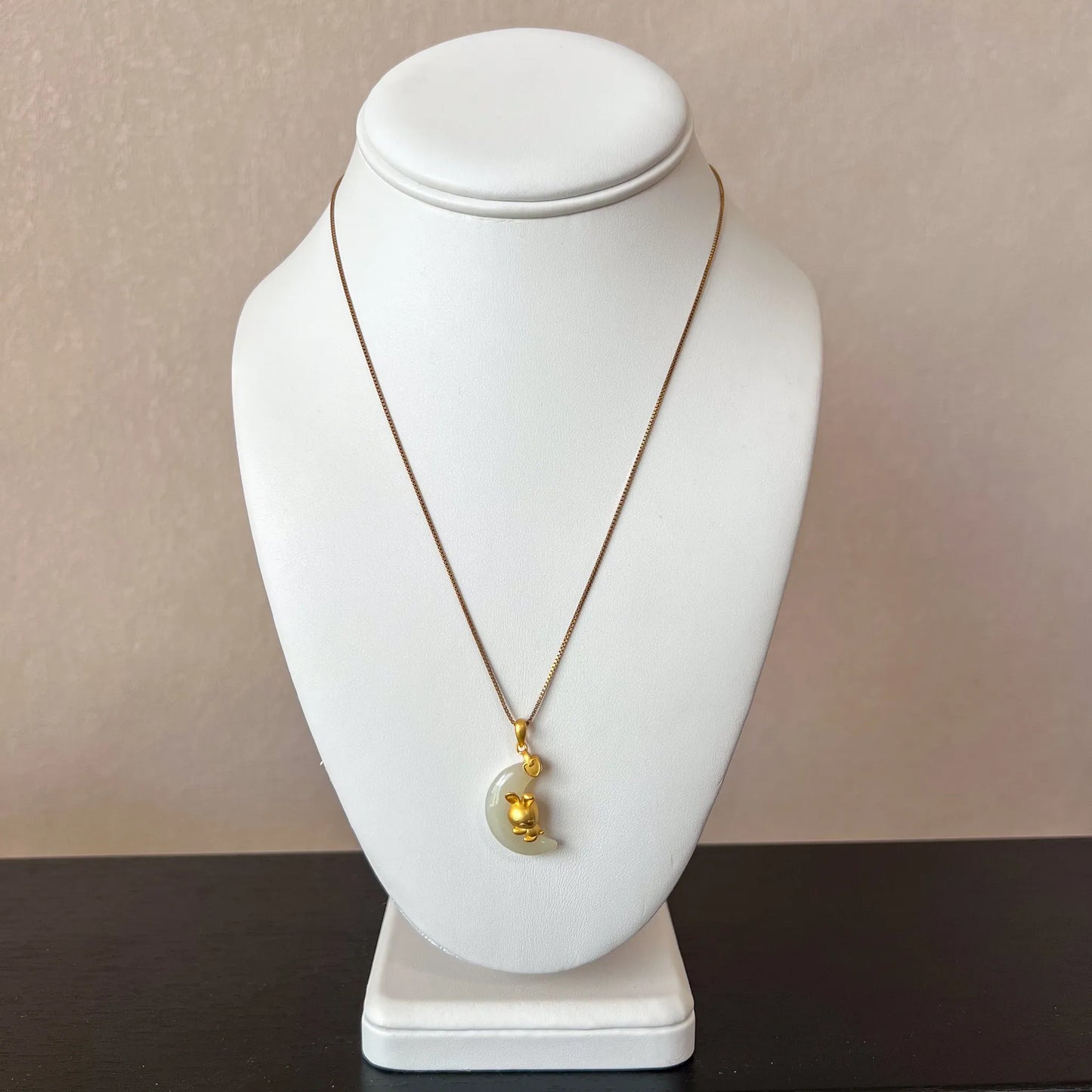 Front-view necklace display of nephrite jade moon rabbit pendant with gold-tone sterling silver chain on white bust stand