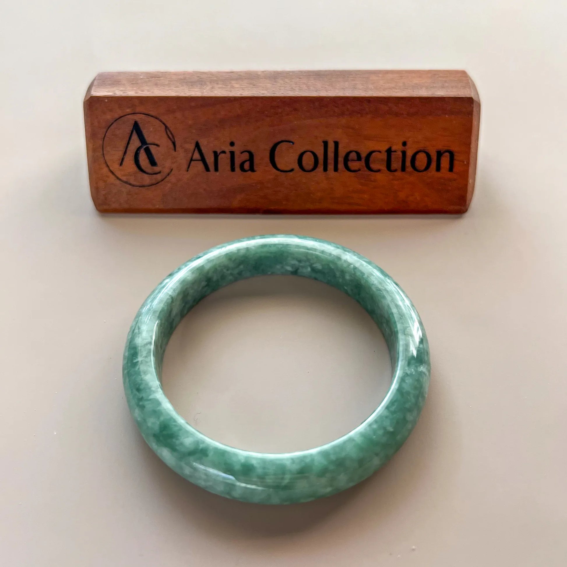 Aria Design Collection mottled green jadeite bangle with a smooth classic profile and polished finish