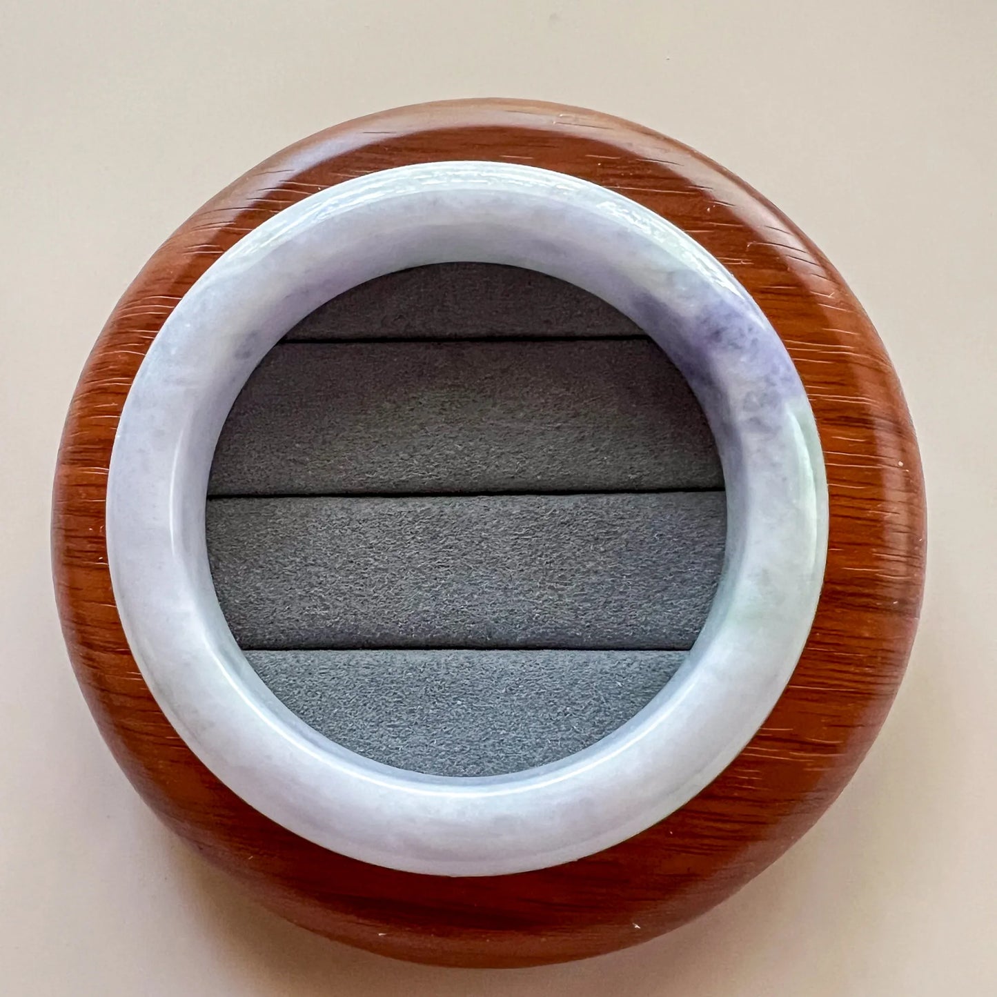 Bangle displayed on wooden stand, polished jade ring with translucent gray cushion insert