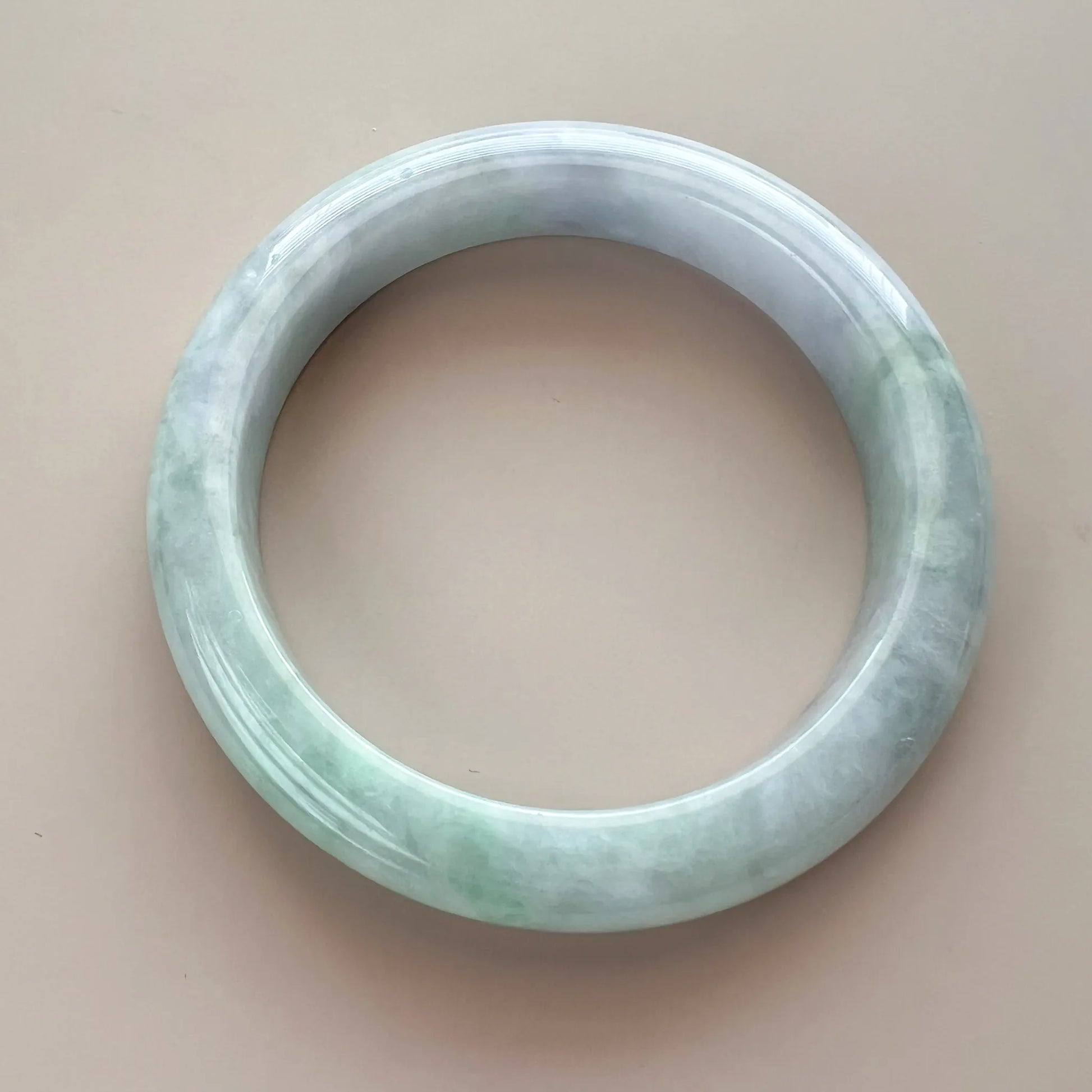Front view of polished jade bangle with pale green and icy white marbling