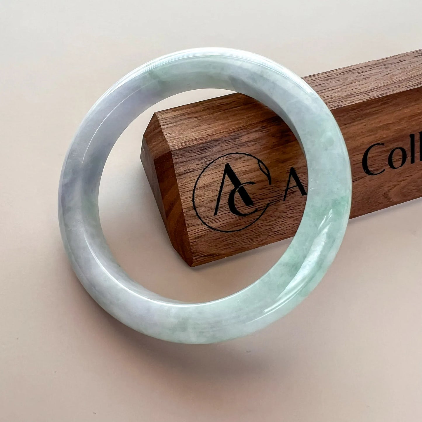 Jade bangle with glossy finish shown beside branded wooden display block