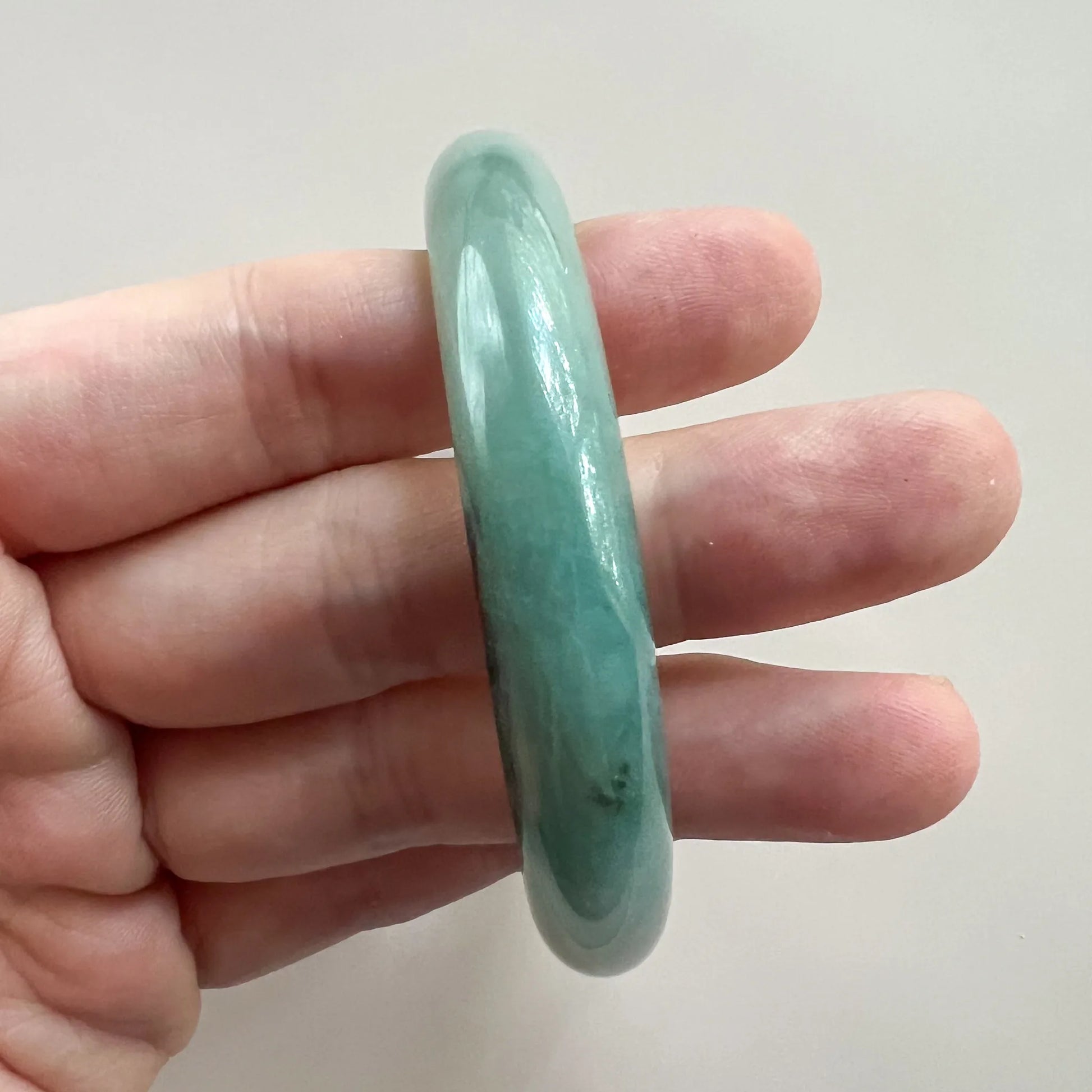 Side profile of smooth green jade bangle showing thickness and rounded edges