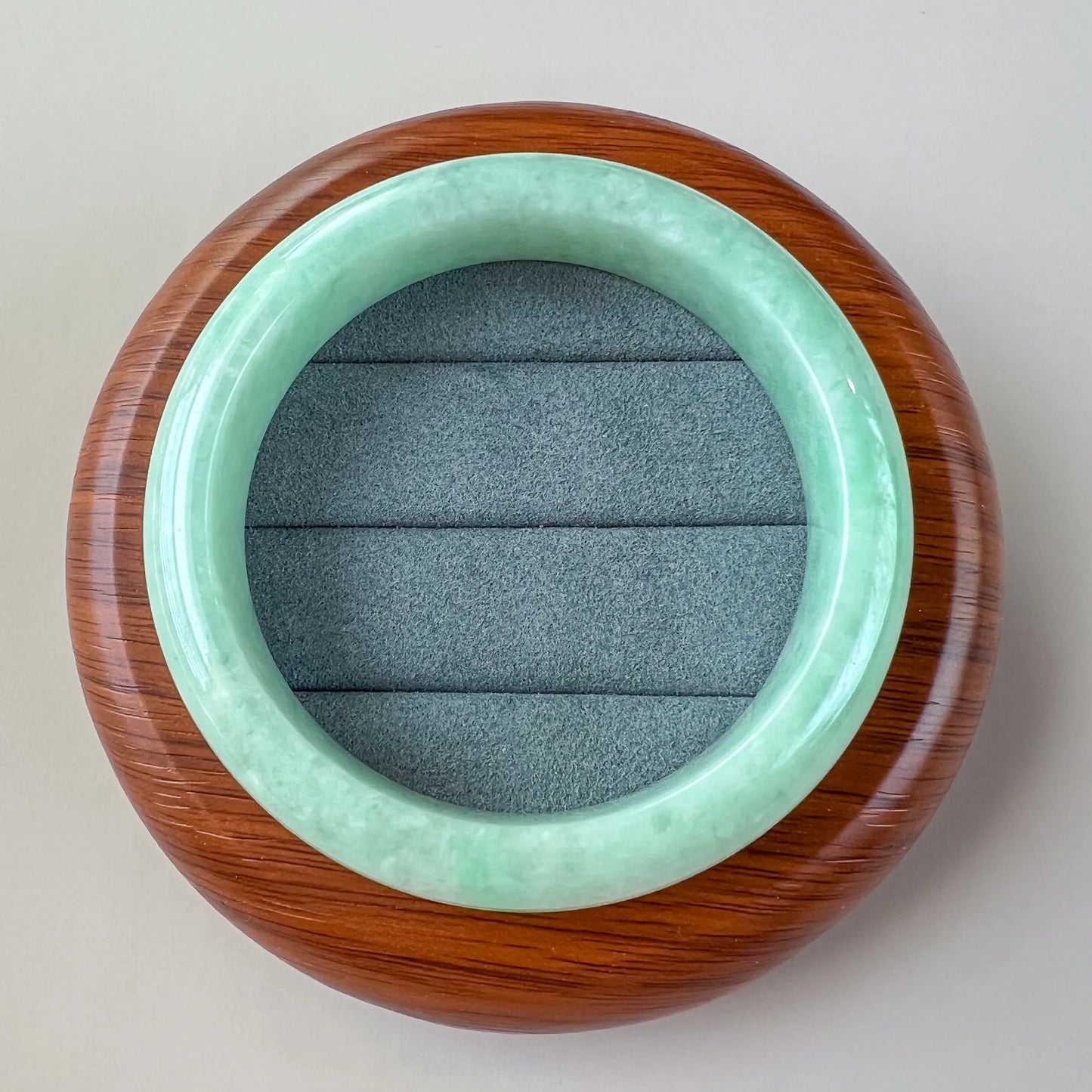Top view of polished jade bangle resting on round wooden display base