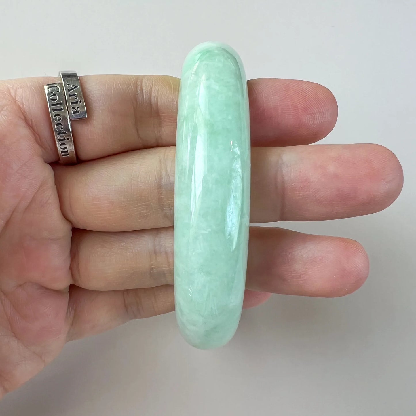 Side profile of smooth mint green jade bangle held in hand