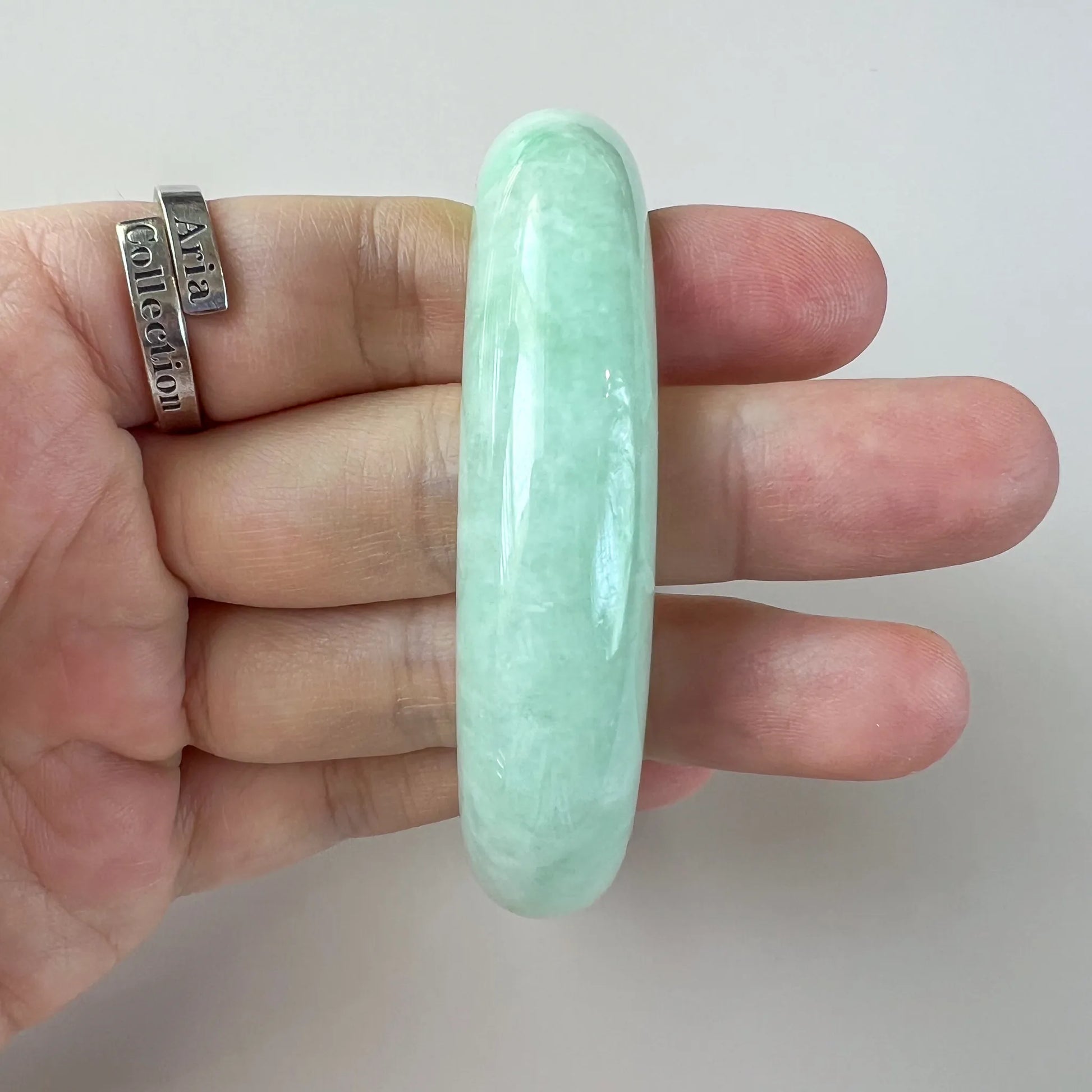 Side profile of smooth mint green jade bangle held in hand