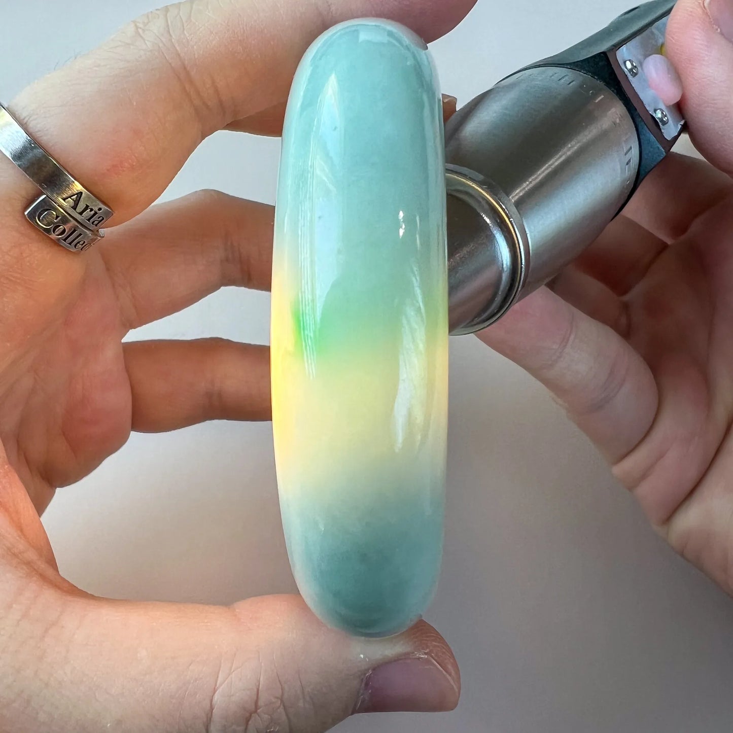 Translucent jade bangle shown under light with soft green and yellow color variation