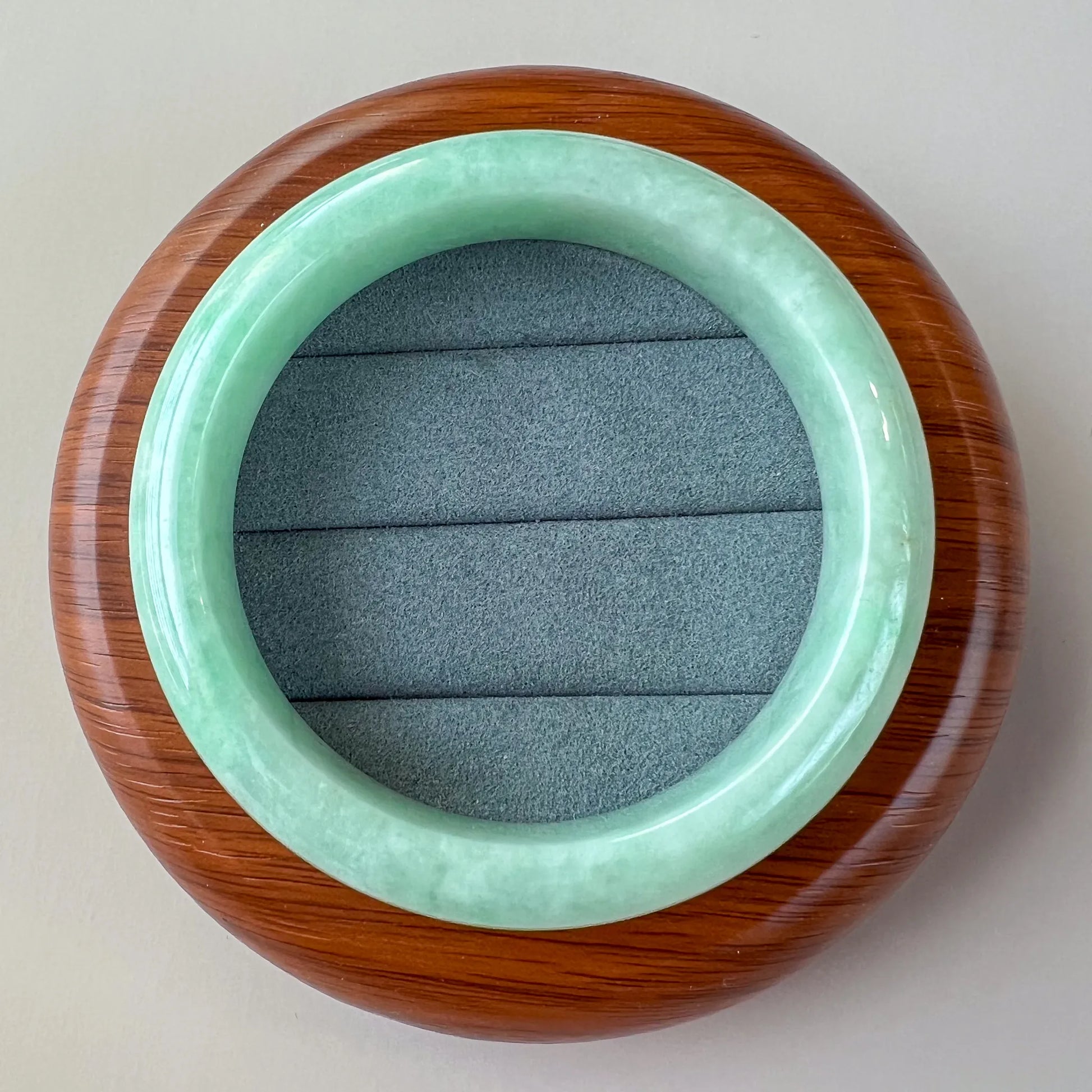 Top view of glossy green jade bangle on round wood stand