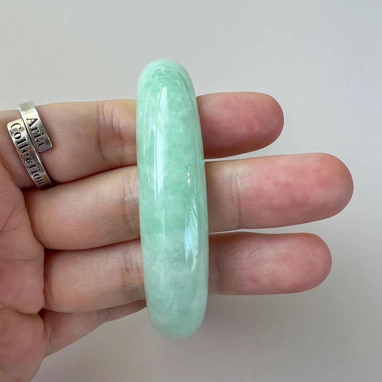 Side profile of rounded green jade bangle showing thickness and polished finish