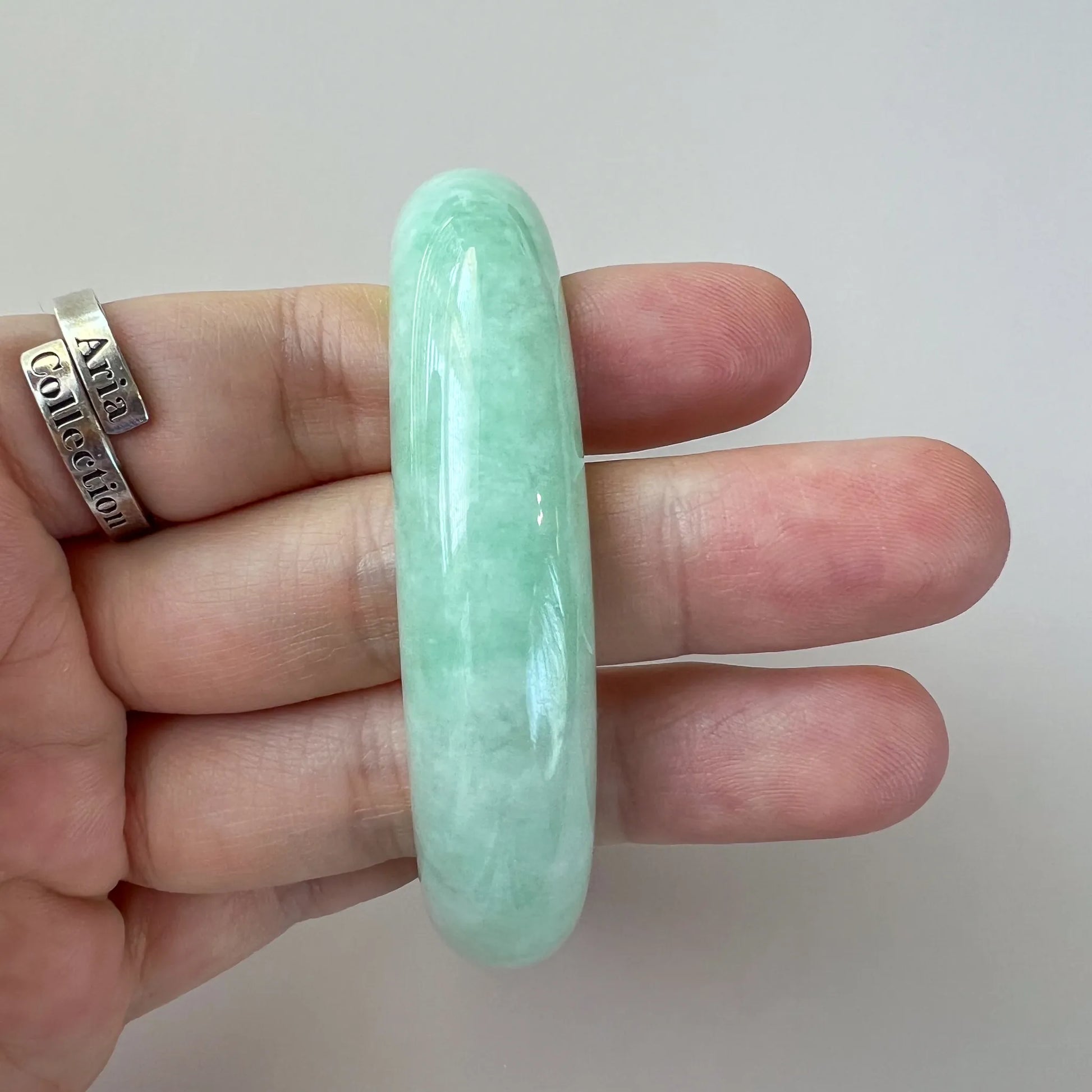 Side profile of rounded green jade bangle showing thickness and polished finish