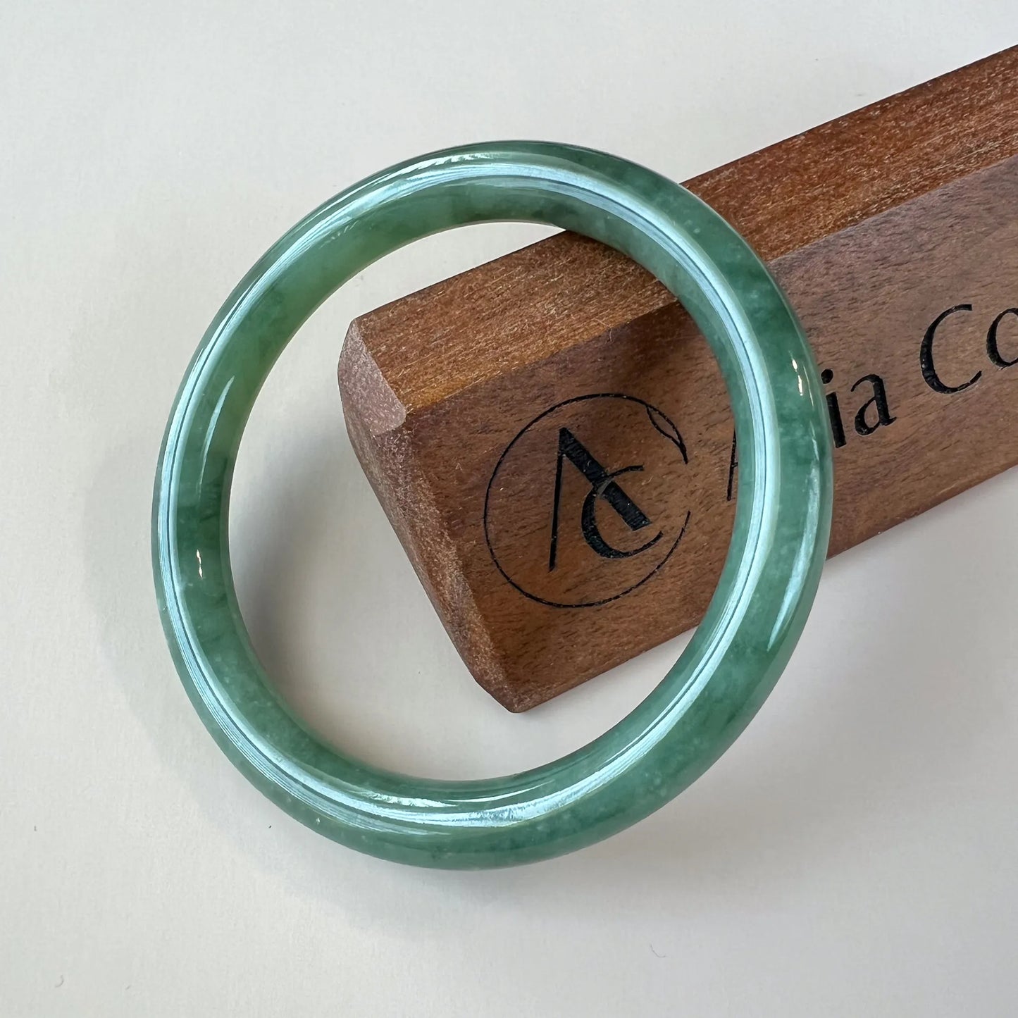 Front view of polished green jade bangle on display stand
