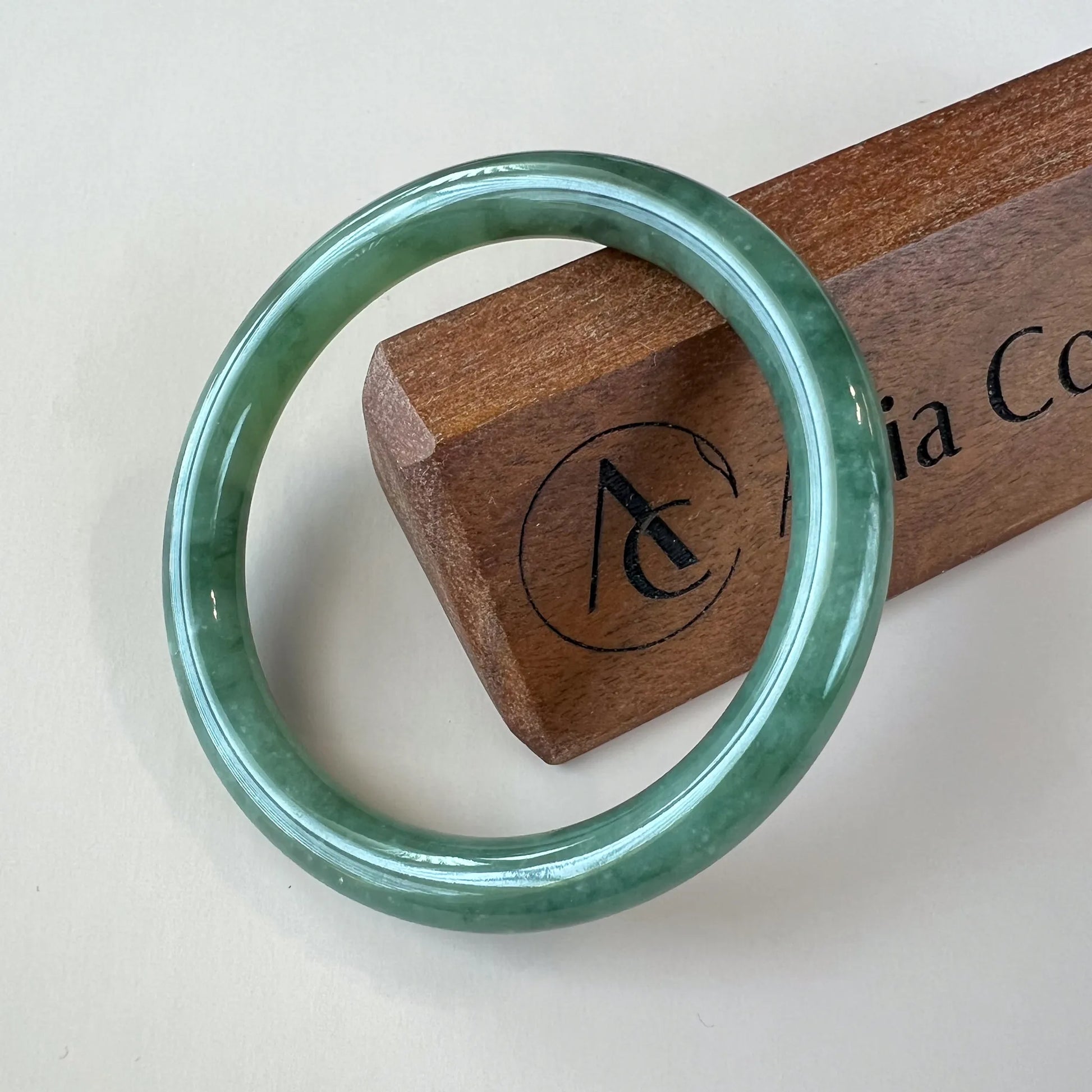 Front view of polished green jade bangle on display stand