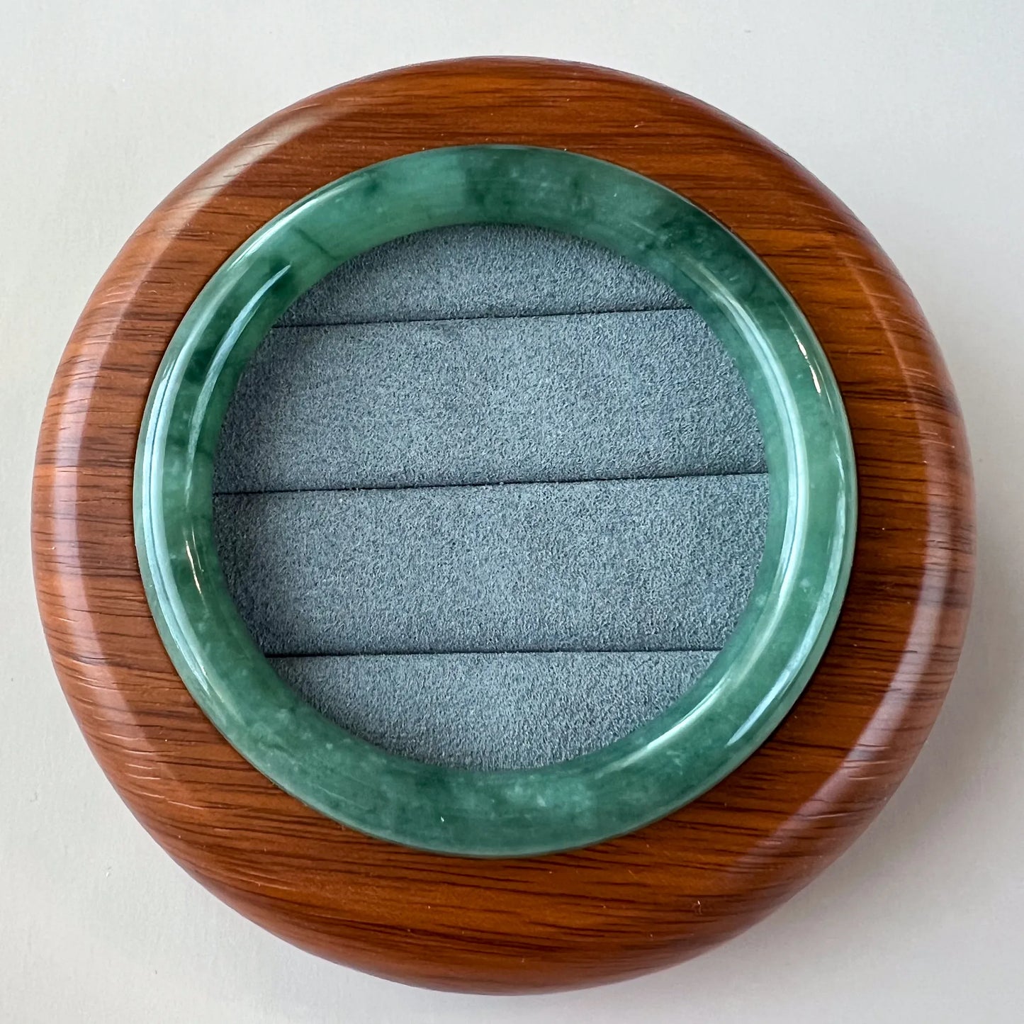 Top view of round green jade bangle in wooden presentation holder
