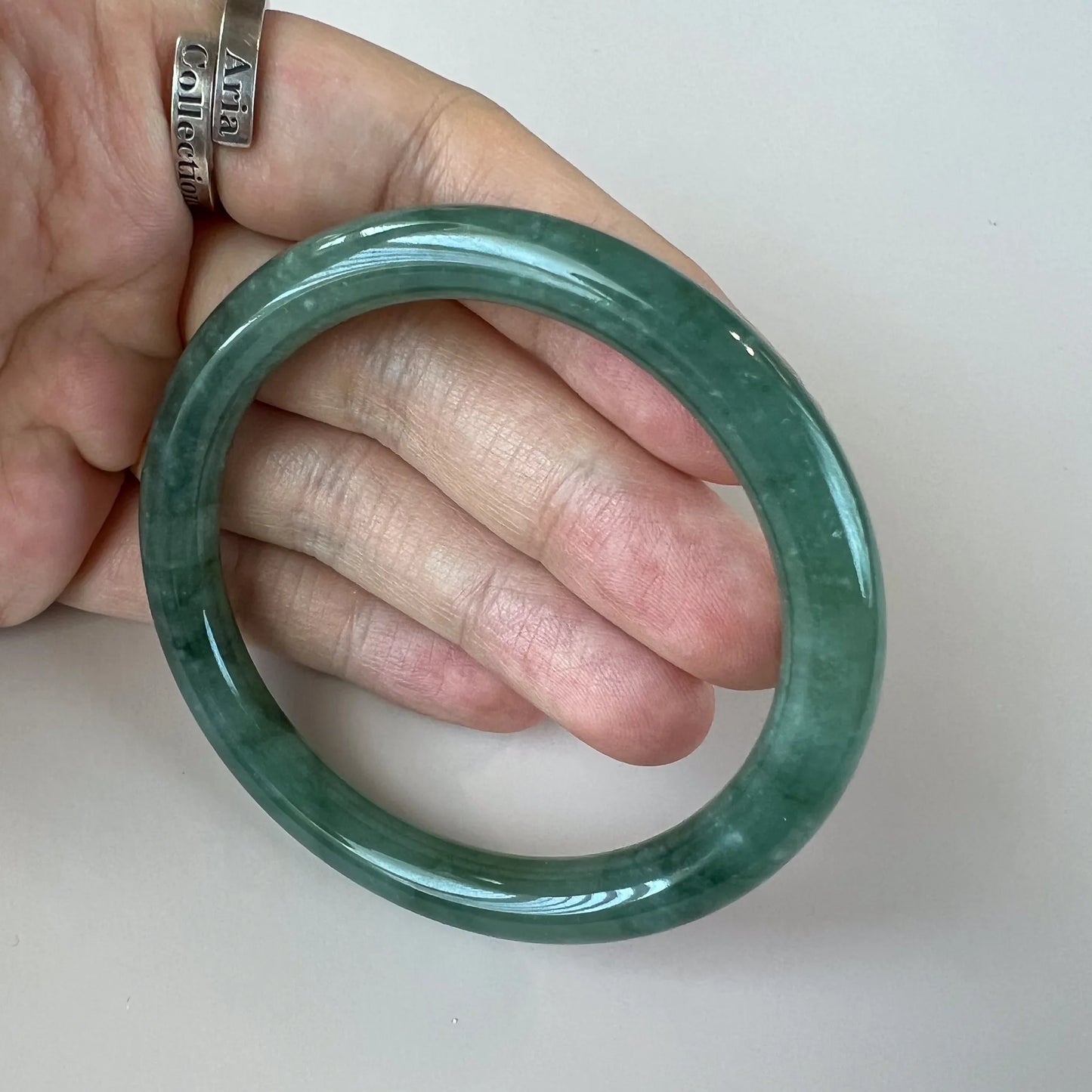 Close hand-held view of translucent green jade bangle with glossy surface
