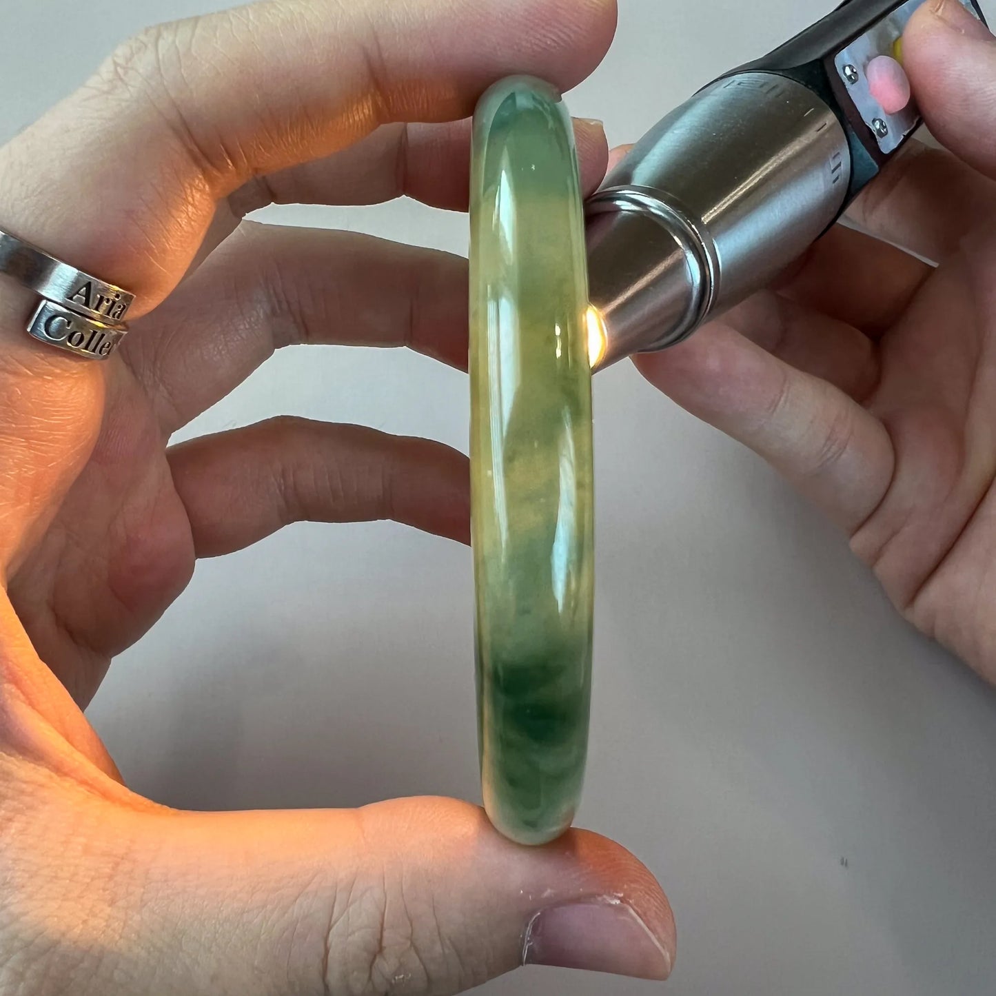 Side profile of translucent green jadeite bangle illuminated to show natural color variation