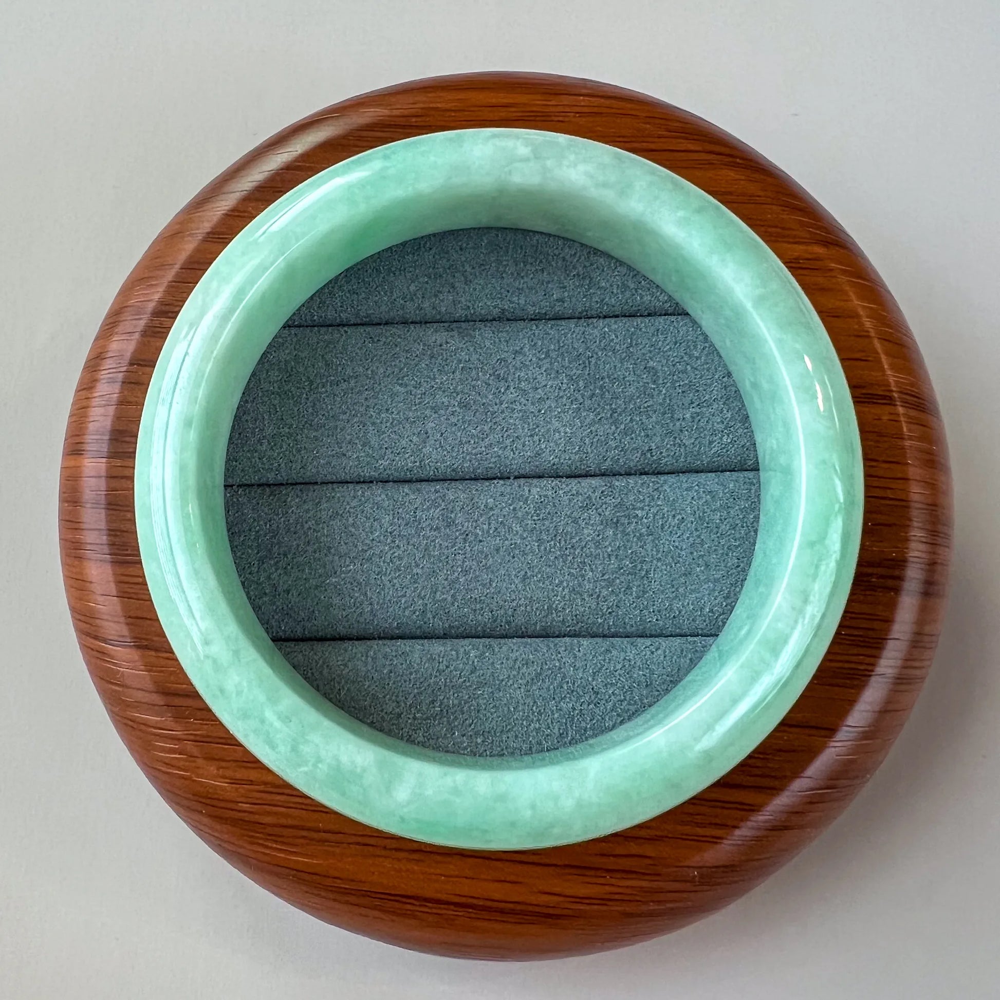 Top-down view of polished jade bangle in wooden display stand