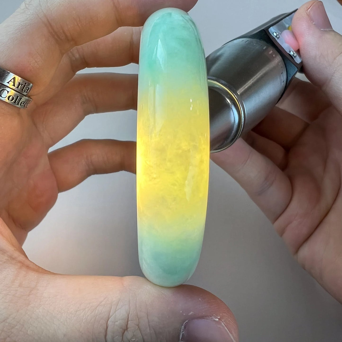 Translucent jade bangle backlit to reveal color variation and polished finish