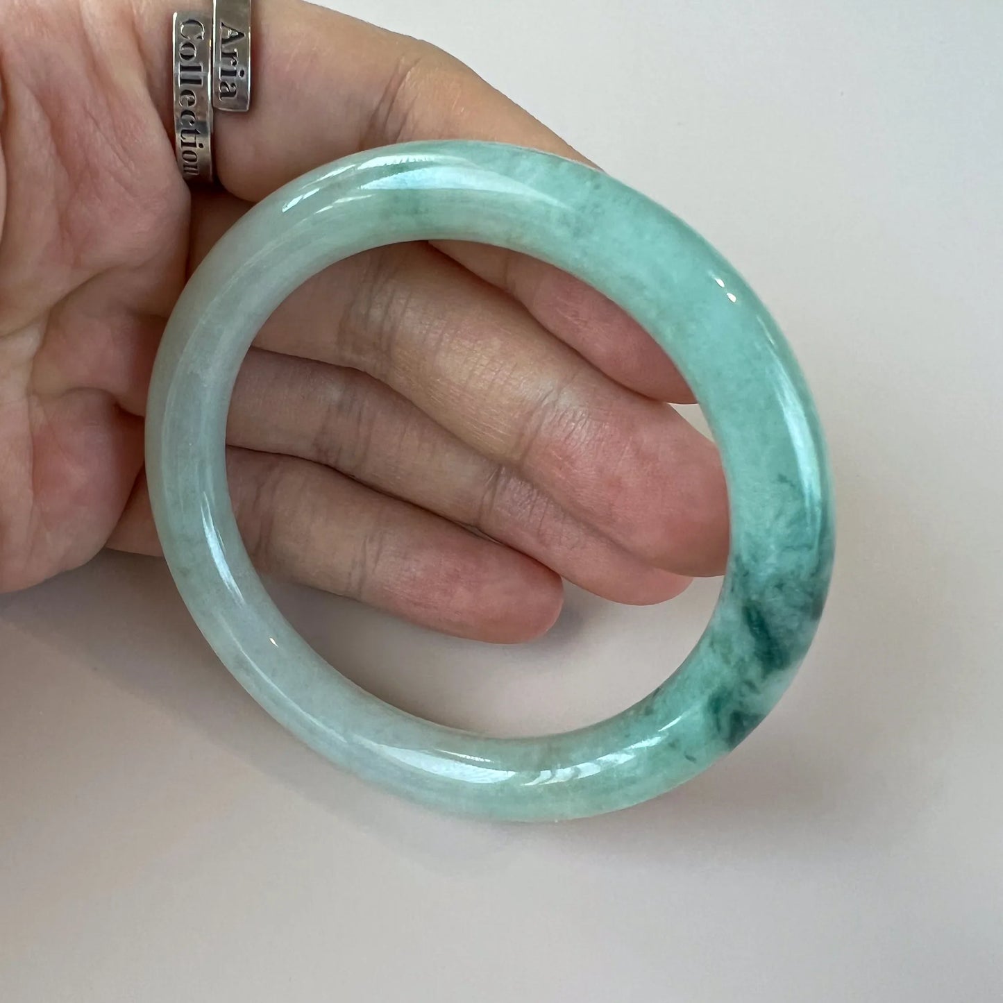 Handheld view of translucent green jade bangle with polished finish