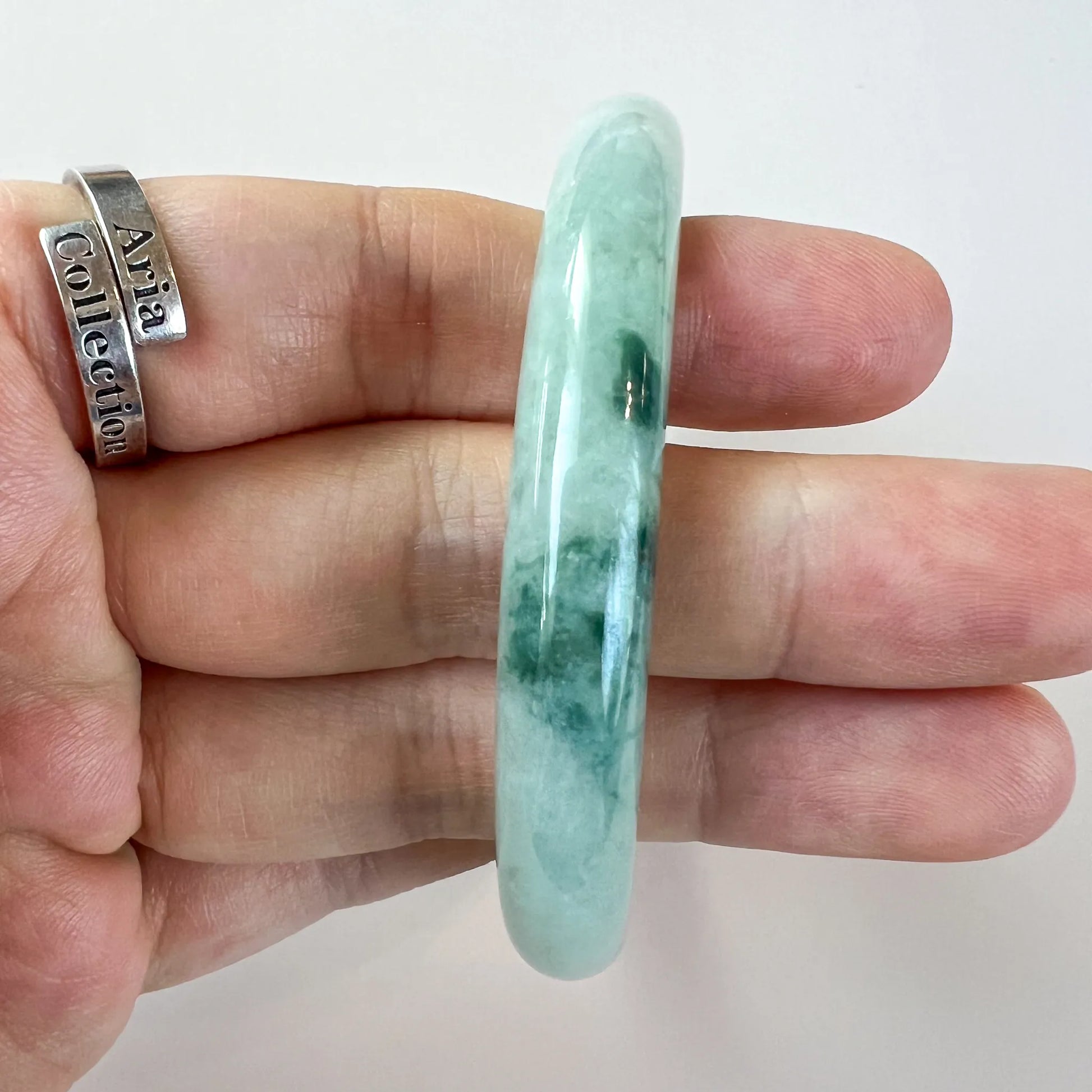 Side profile of smooth jade bangle showing thickness and mottled color