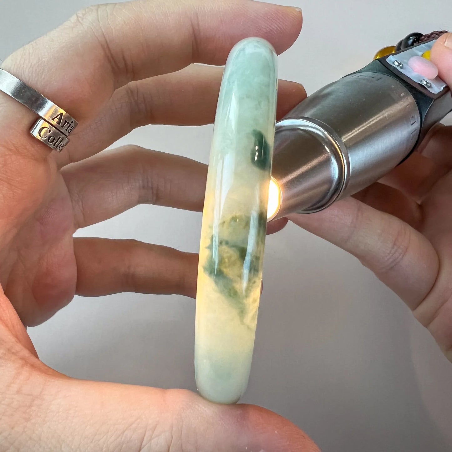 Side view of translucent jade bangle held under light to show color