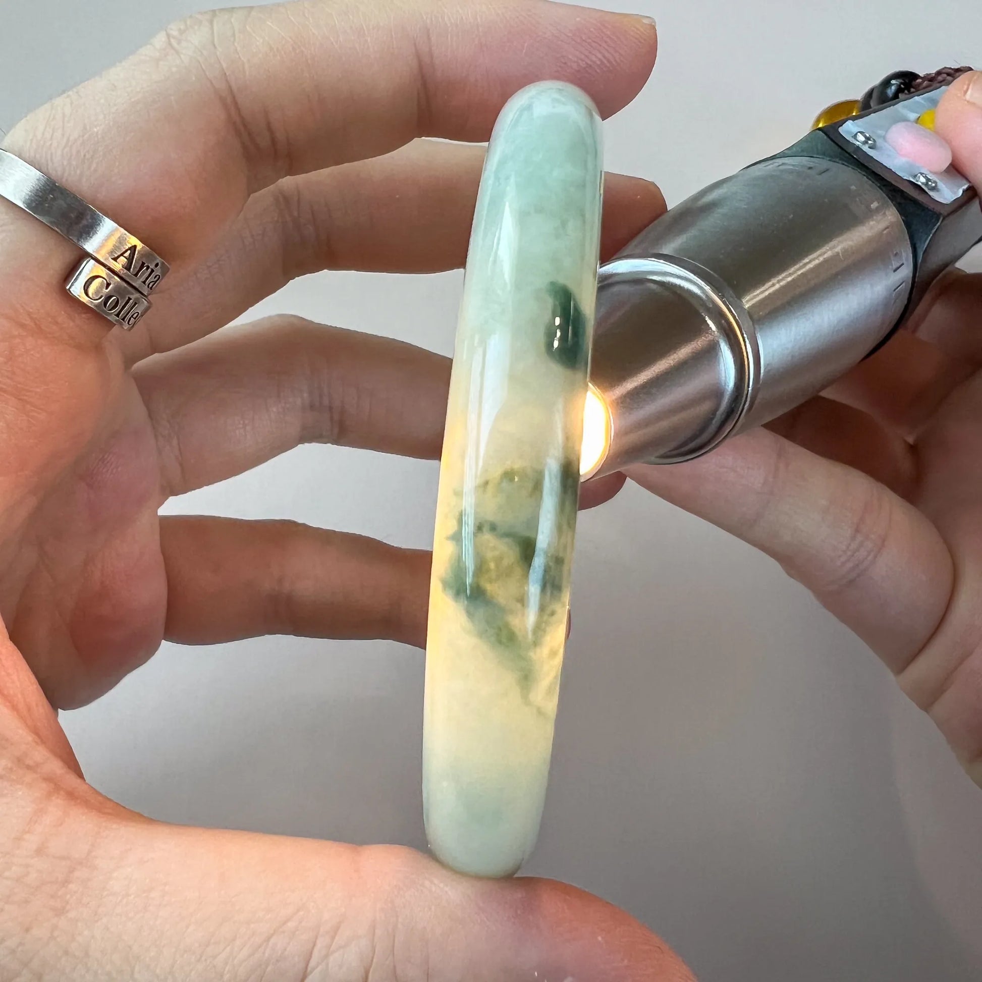 Side view of translucent jade bangle held under light to show color