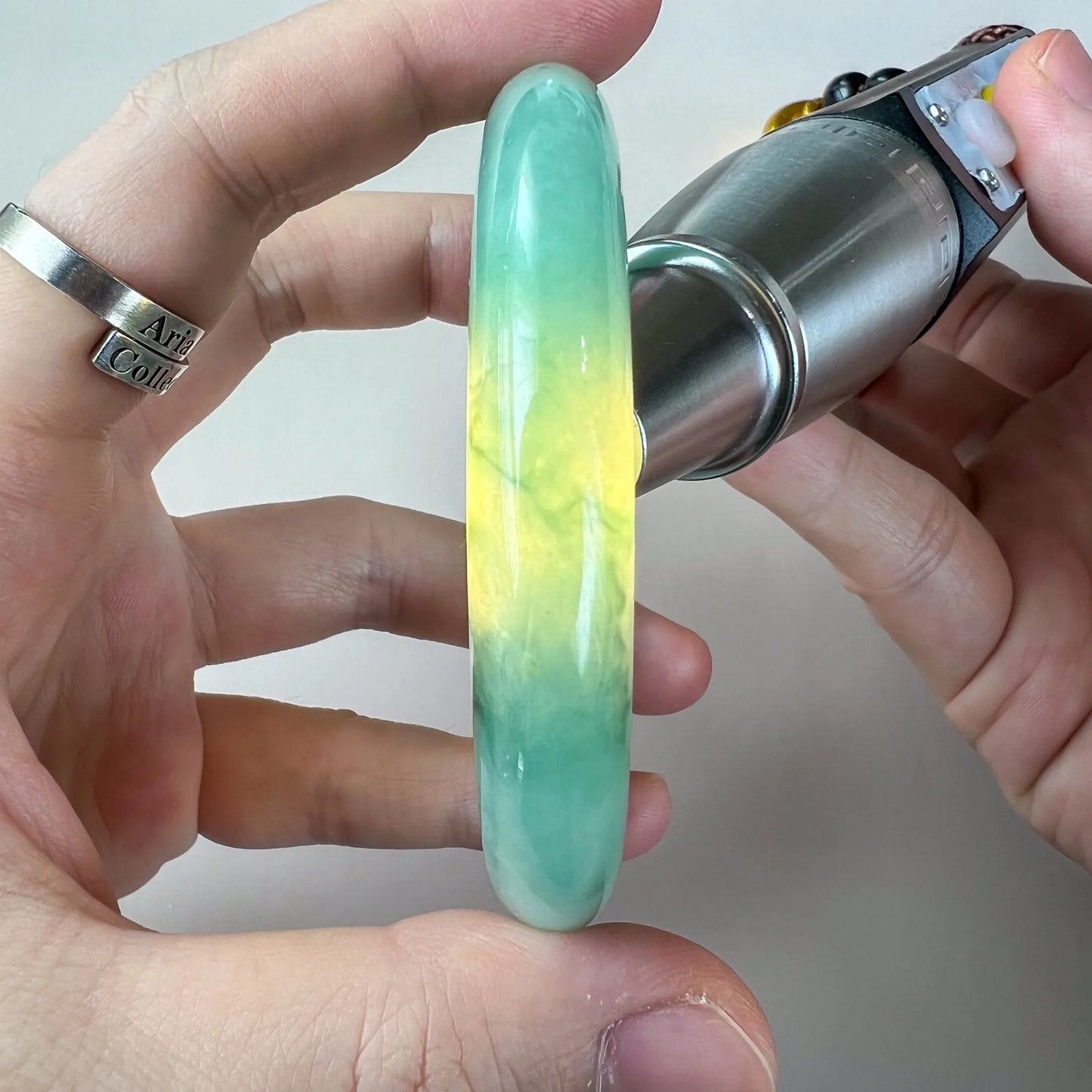 Side profile of polished jade bangle with translucent yellow center and green edges